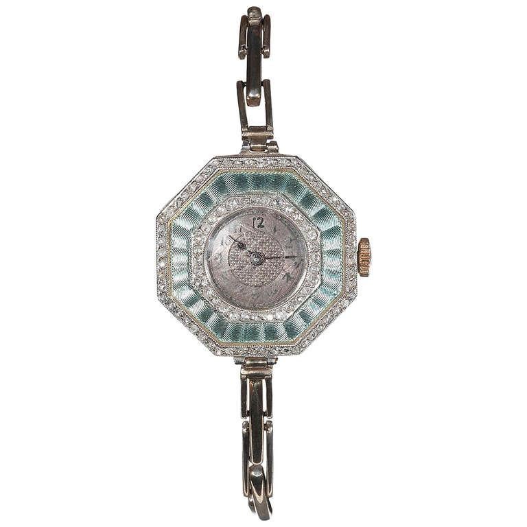 
Art deco lady's gold, platinum, enamel and diamond bracelet watch of octagonal shape, guilloche seawater-color enamel, mounted in platinum and yellow gold. Two pattern dial, Arabic numerals, manual-wind movement, stretch bracelet, circa 1920.