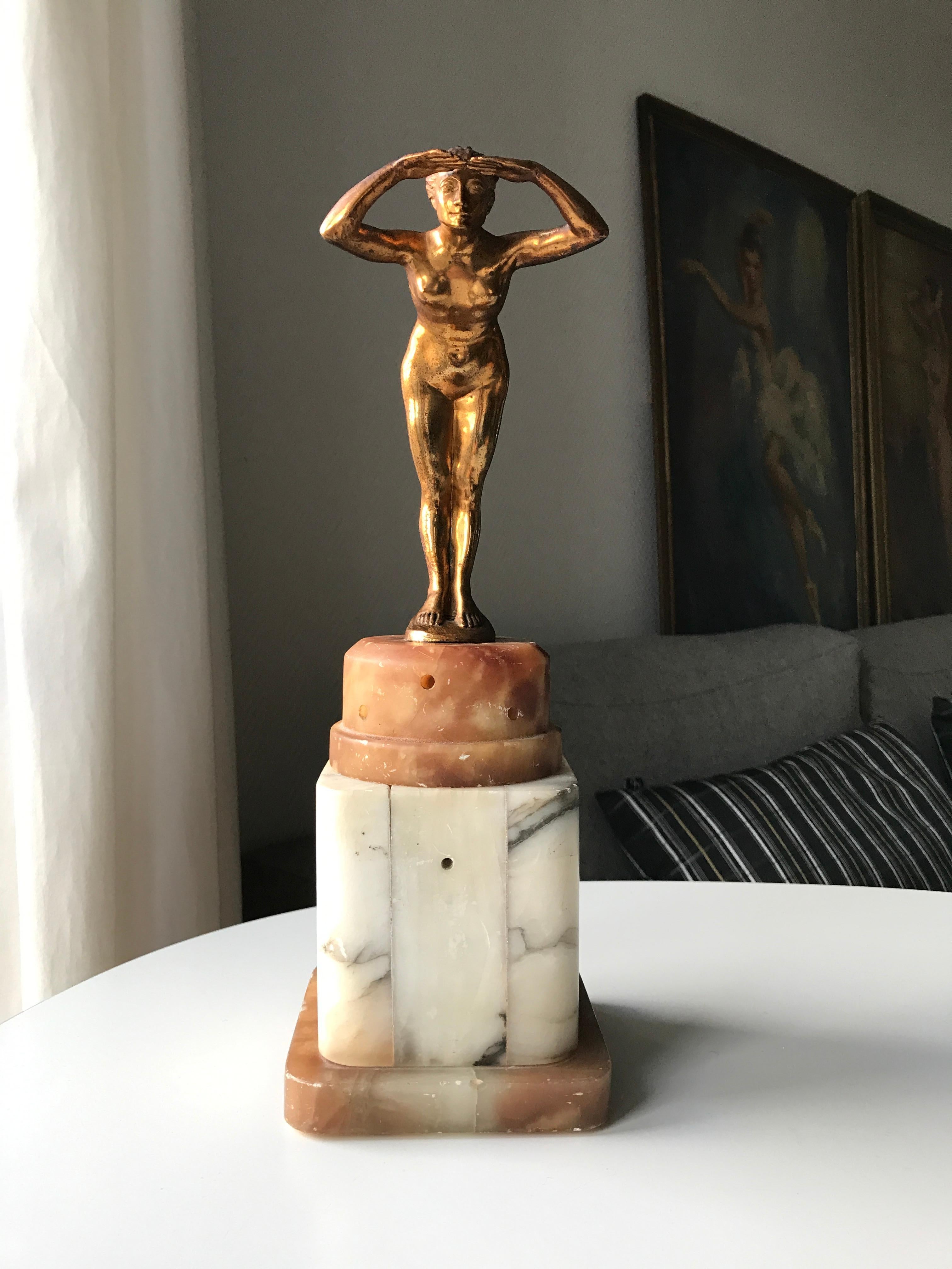 Art Deco table lamp with figurine of Naked Lady. Lamp base in two colored alabaster with marble effects. Figurine of beautiful woman made of guilted metal scouting into the horizon. The base has a function as an ozon / perfume lamp. This meant that