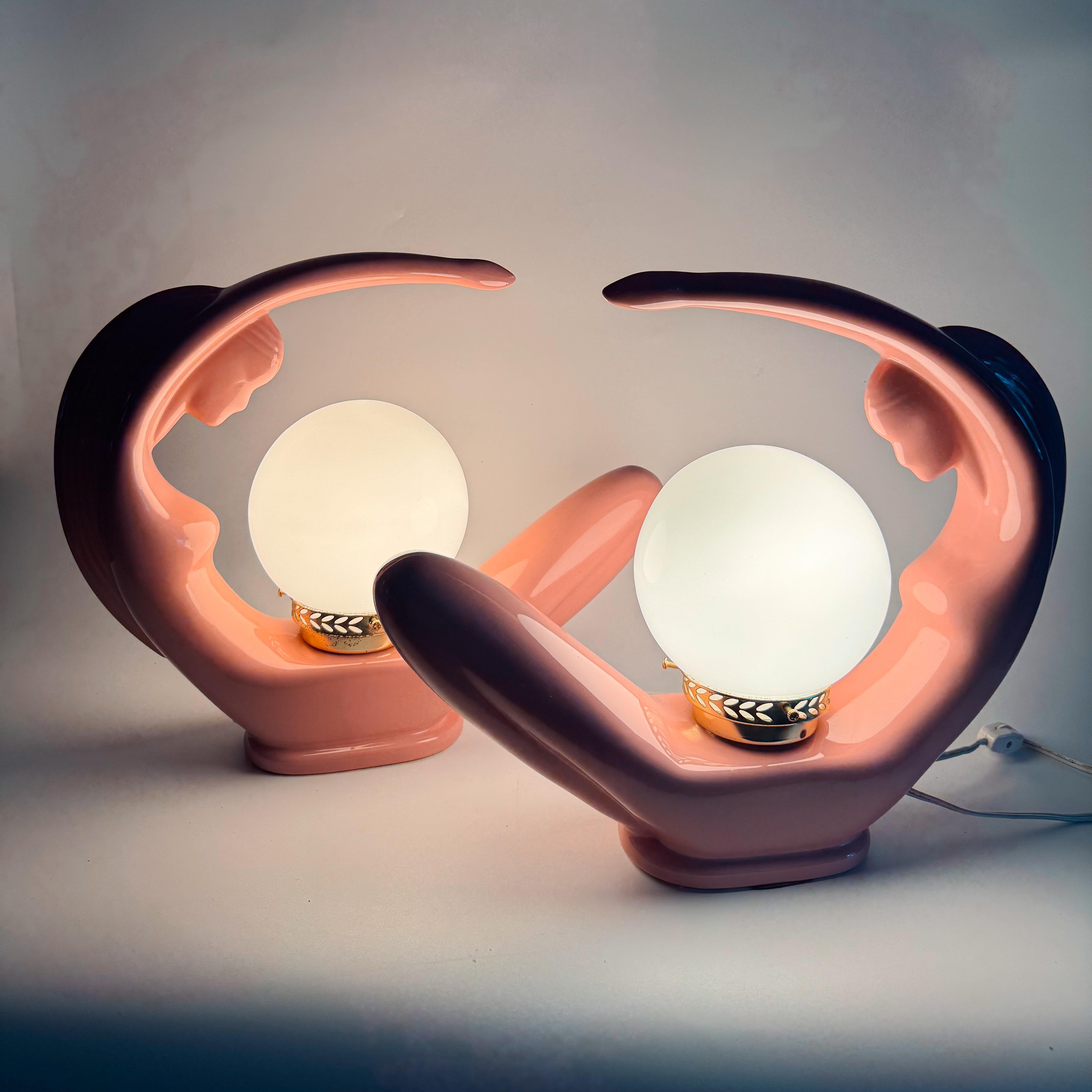 Un llamativo par de esculturales lámparas lady de los años 80, fabricadas en cerámica rosa brillante y llenas de encanto retro. Cada figura sostiene con gracia un orbe brillante, creando la ilusión de movimiento y luminosidad, como diosas en