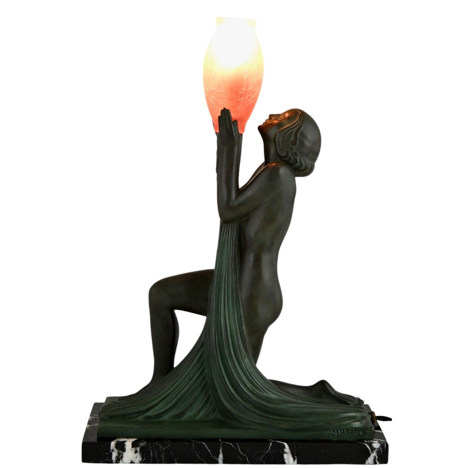 Art Deco lamp ADORATION nude with vase by Raymonde Guerbe.
Cast at the Max Le Verrier foundry.
Patinated art metal, black marble base, red glass vase.
France ca. 1940. 
This lamp is illustrated in:
Max le Verrier, un esprit Art Déco.  
Bénédicte