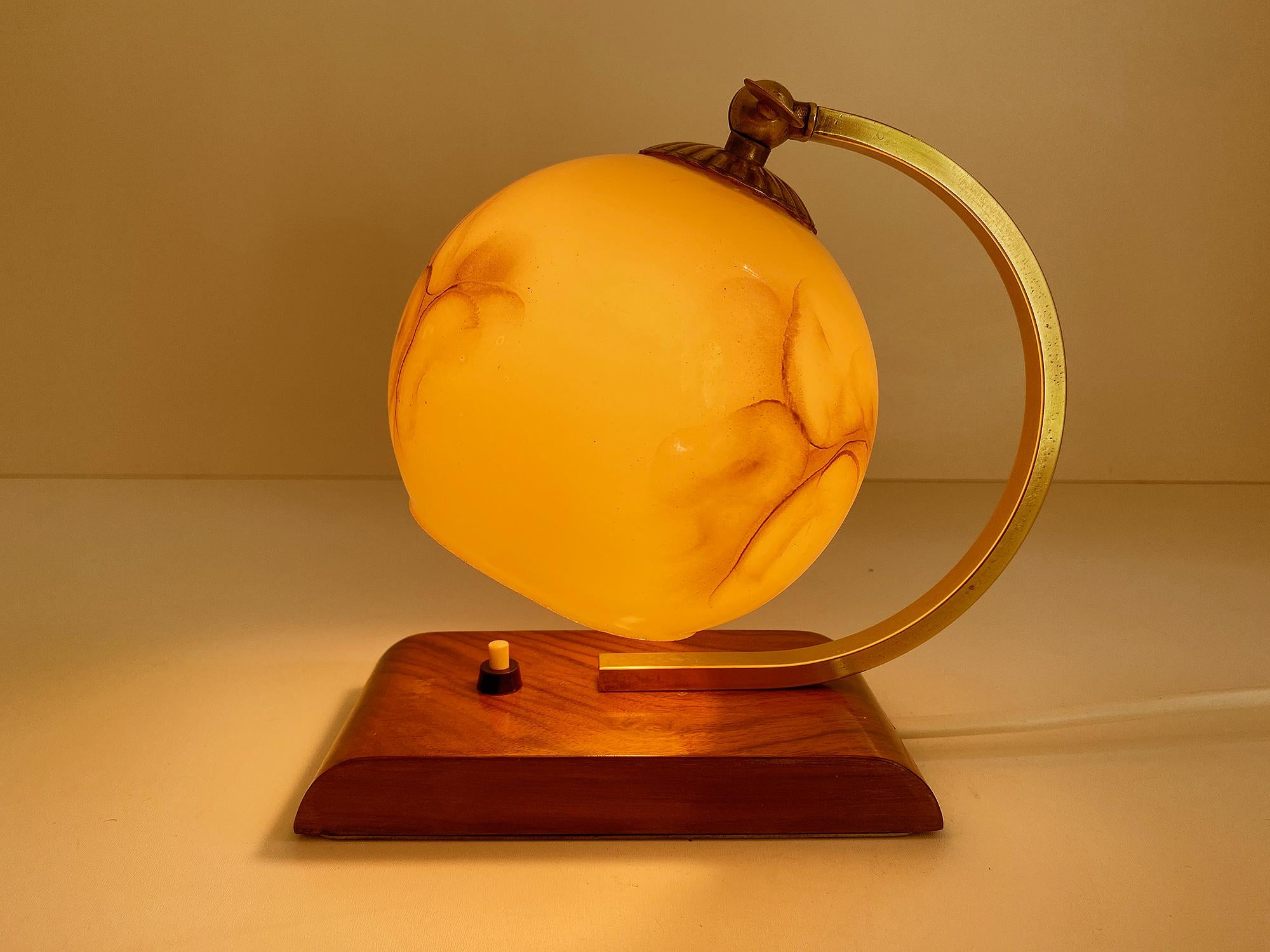 Art Deco Bauhaus table lamp featuring a streamlined wooden base, half circle brass cradle and marbleized opaline glass shade, 1930s  The shade’s angle can be adjusted. - fully rewired - The lamp has been tested with US American light bulbs under