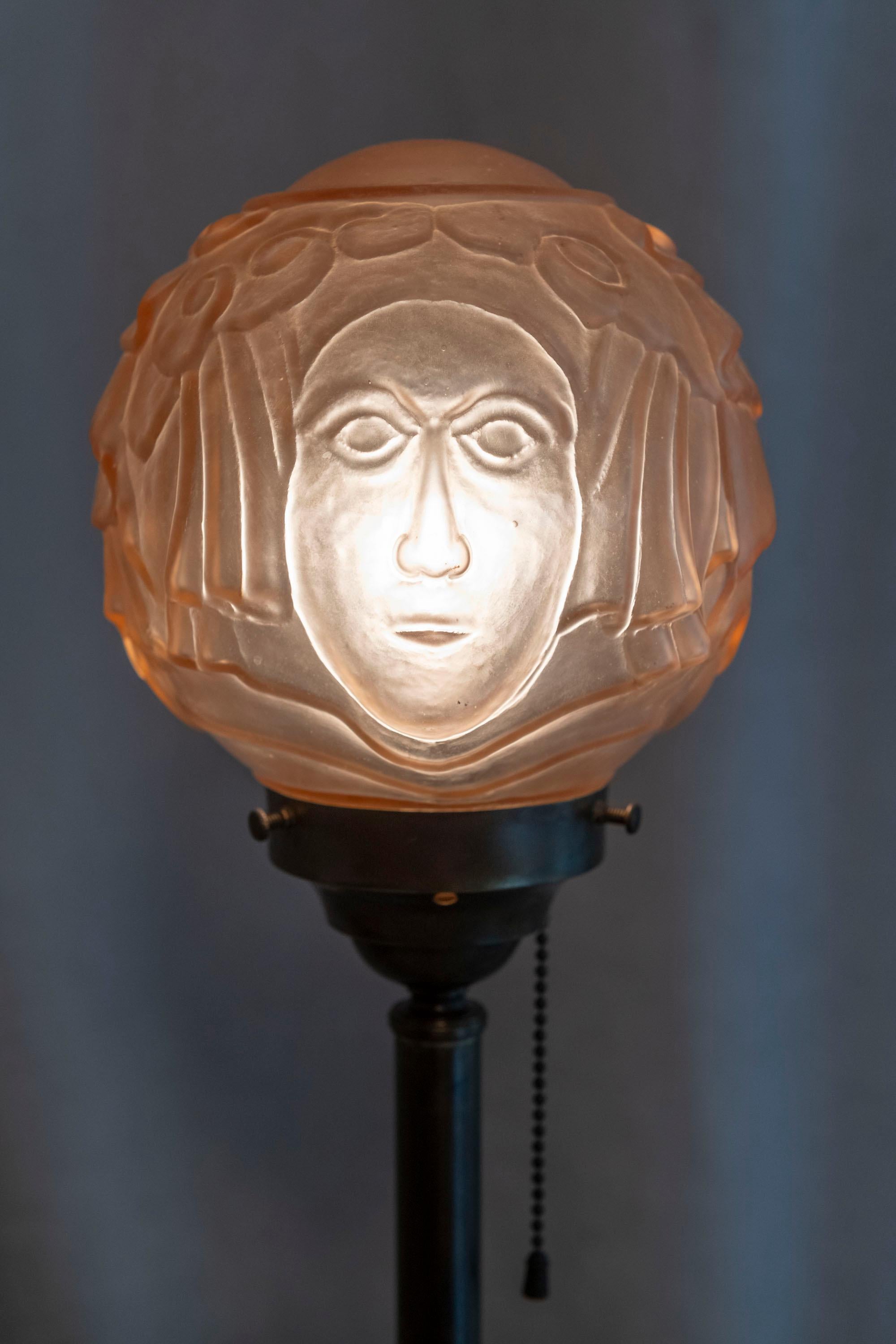  Cette lampe inhabituelle est une belle combinaison d'une base en bronze moulé de qualité et d'un abat-jour en verre égyptien spécial avec des visages sur deux côtés. Elle est américaine et a été réalisée dans les années 1920. Nous ne savons pas qui