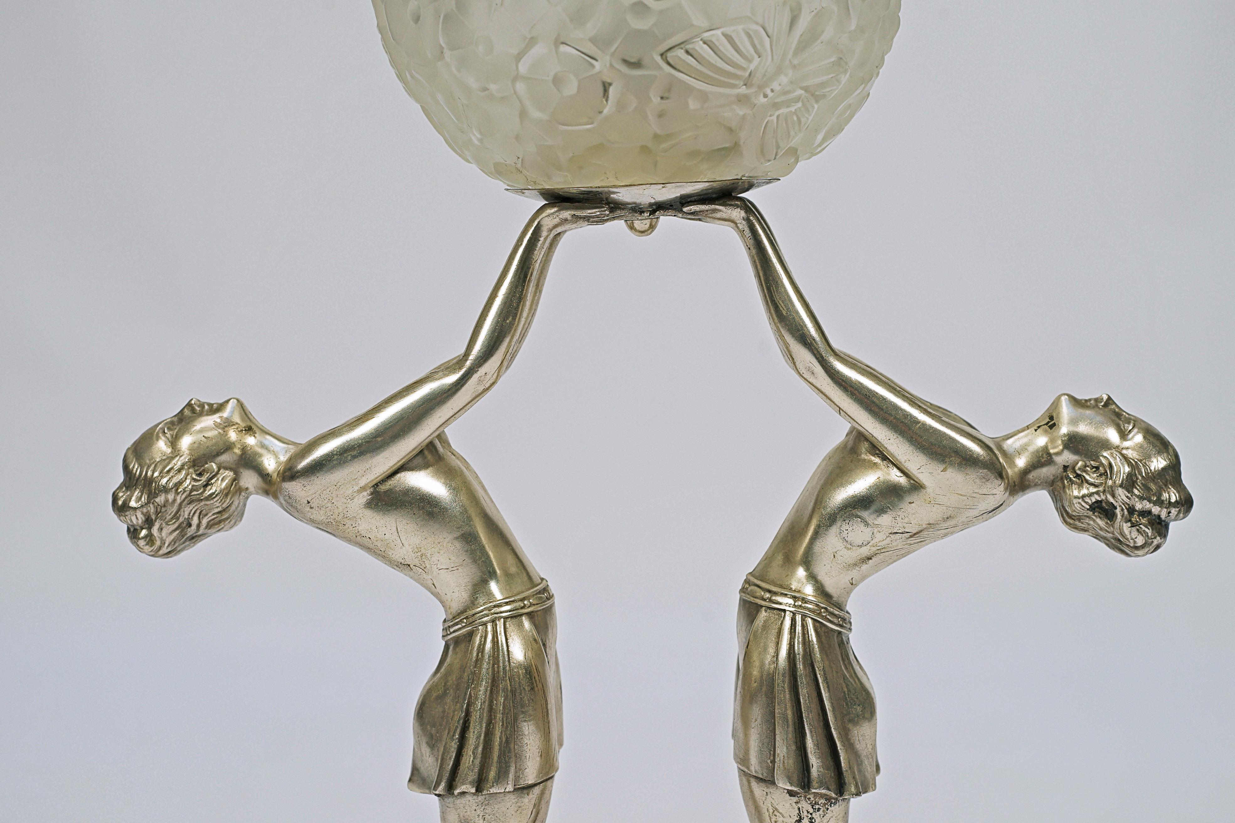 Lámpara de sobremesa Art Decó, de bronce plateado, con base de mármol y globo de cristal satinado, que representa a dos mujeres sosteniendo una esfera, diseñada por Enrique Molins-Balleste (1893-1958). Firmado Balleste.

Francia, CIRCA 1920.