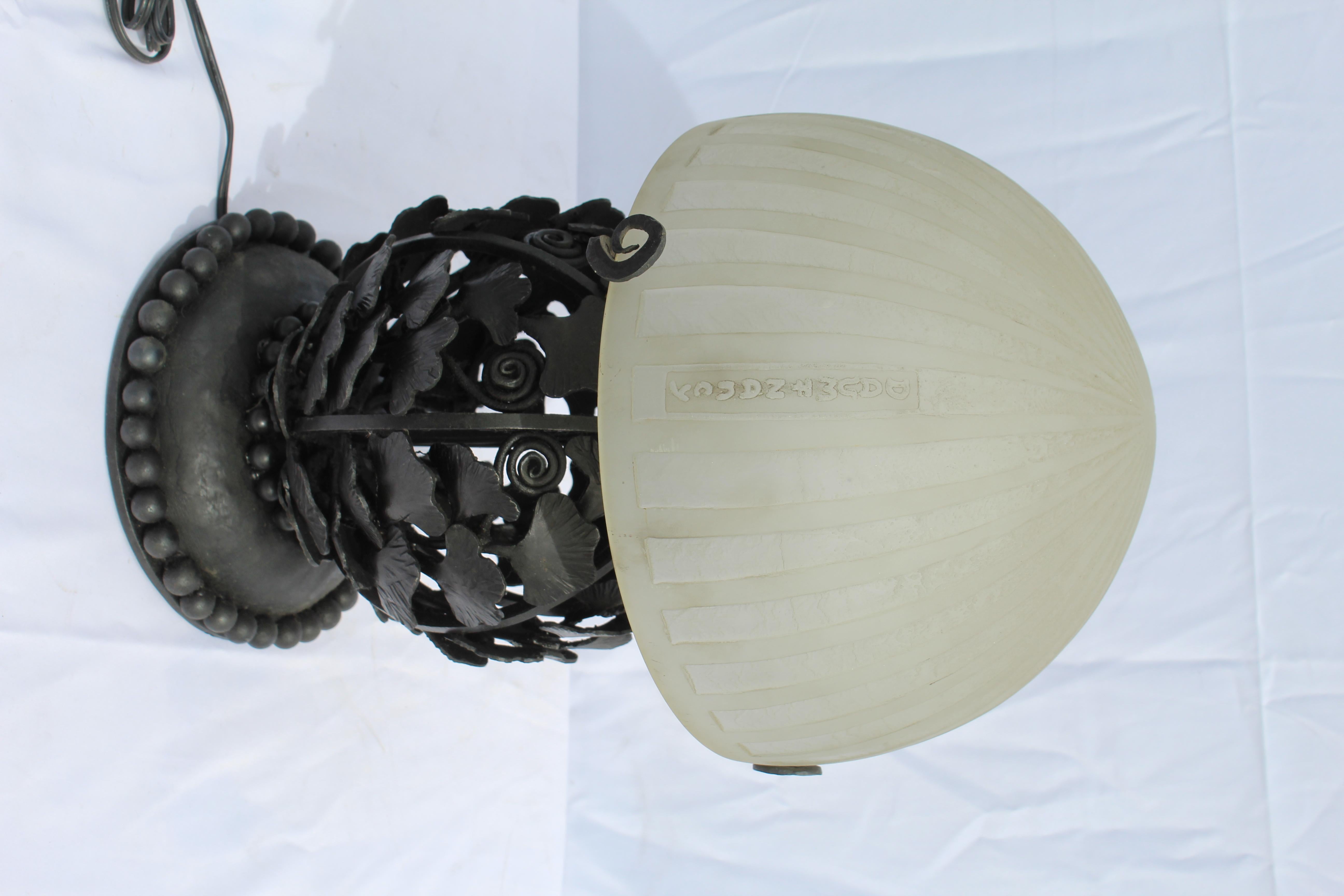 Lampe Art Déco réalisée d'après le grand E. Brandt et dotée d'un abat-jour taillé à l'acide de style Daum. Abat-jour avec nom illustré. Tous après l'original. Excellent travail du métal sur les feuilles de Ginko. Base lourde . Provenant d'un