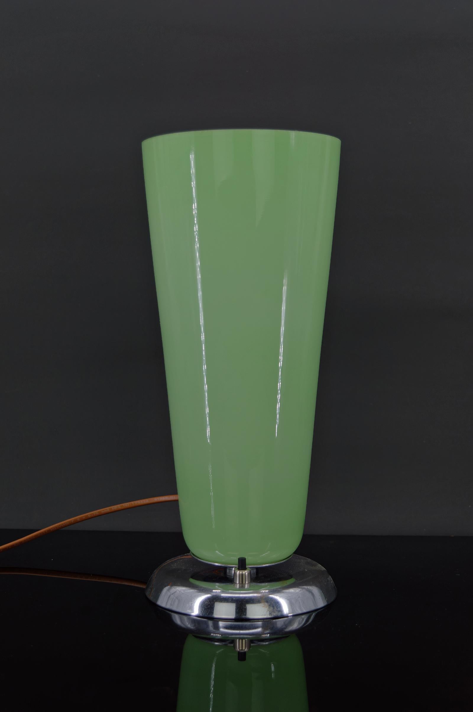 Belle lampe de table / bureau avec une base en métal chromé sur laquelle repose un verre opalin de couleur vert / céladon.

Art déco, France, vers 1930.

Bon état, restauré : matériaux électriques changés et nouveau bouton poussoir