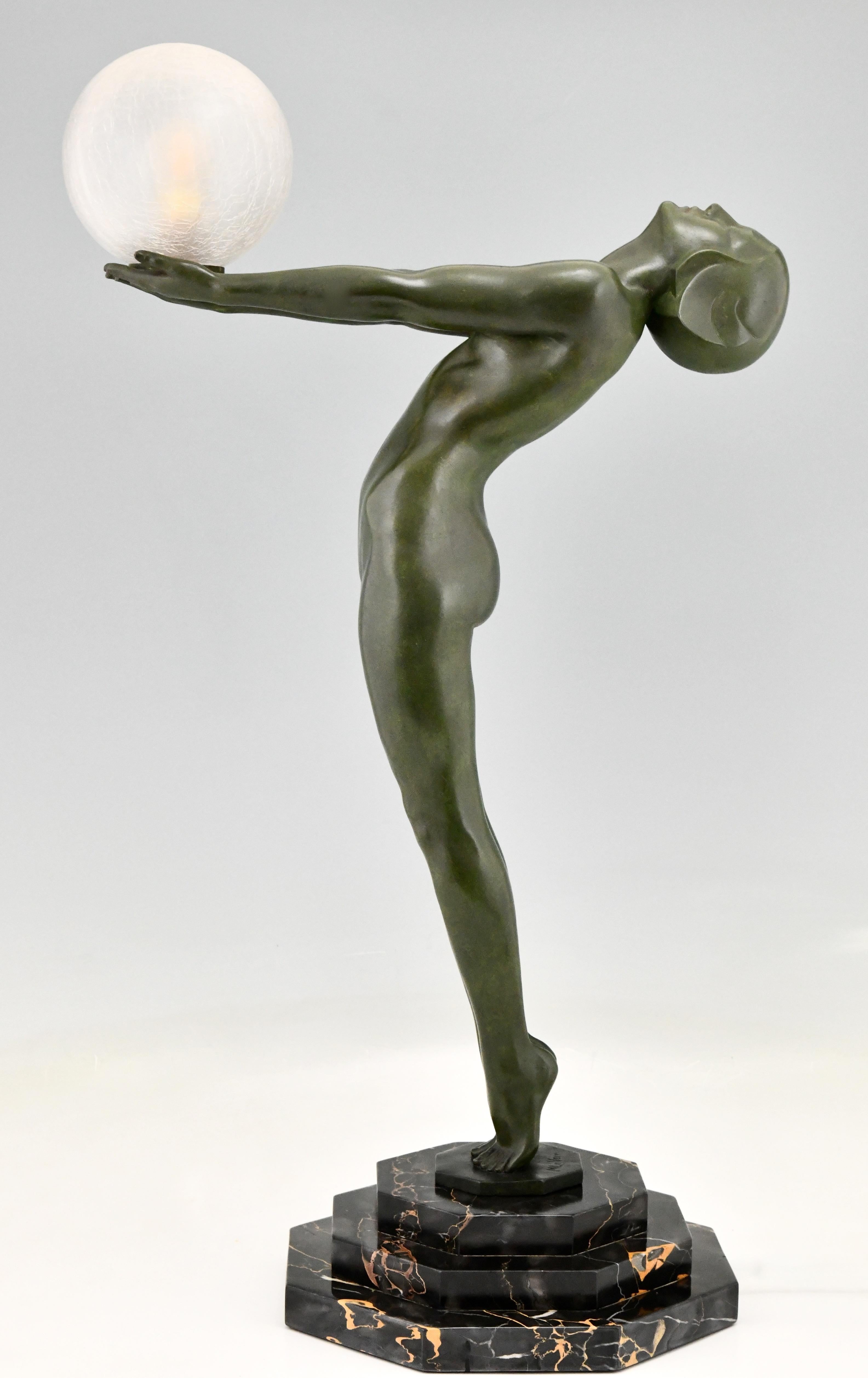 Impressive Art Deco figural table lamp of a standing nude holding a glass shade, Clarté by the famous French sculptor Max Le Verrier. H. 84 cm / 33 inch. France 1928. Art Metal with green patina, on a octagonal Portor marble base and with crackled