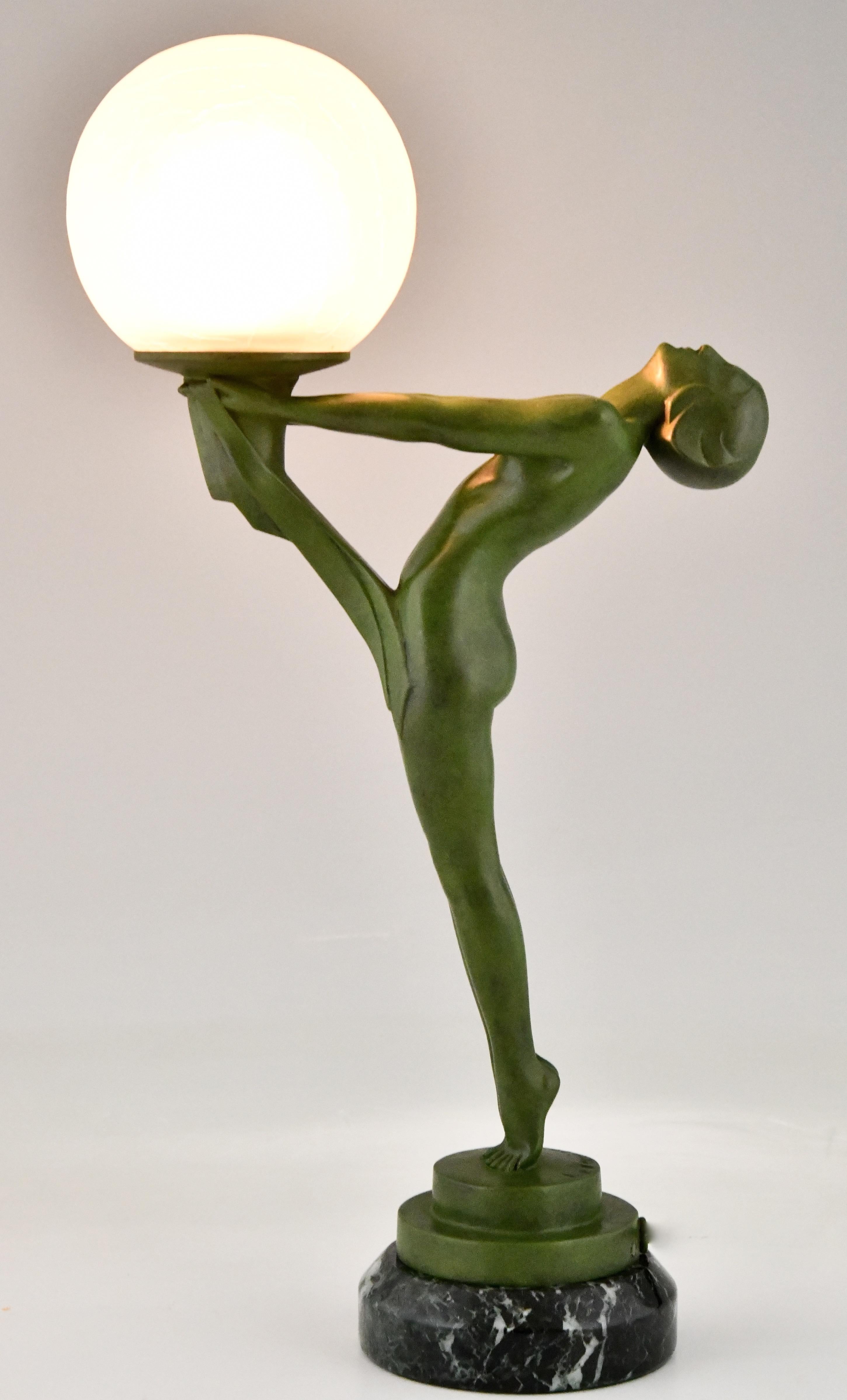 Art Deco lamp standing nude with ball by Max Le Verrier. This figural table lamp is the smaller version of the famous Clarté model. The statue is executed in Art metal with green patina and stands on a circular green marble base. France 1930. 

A