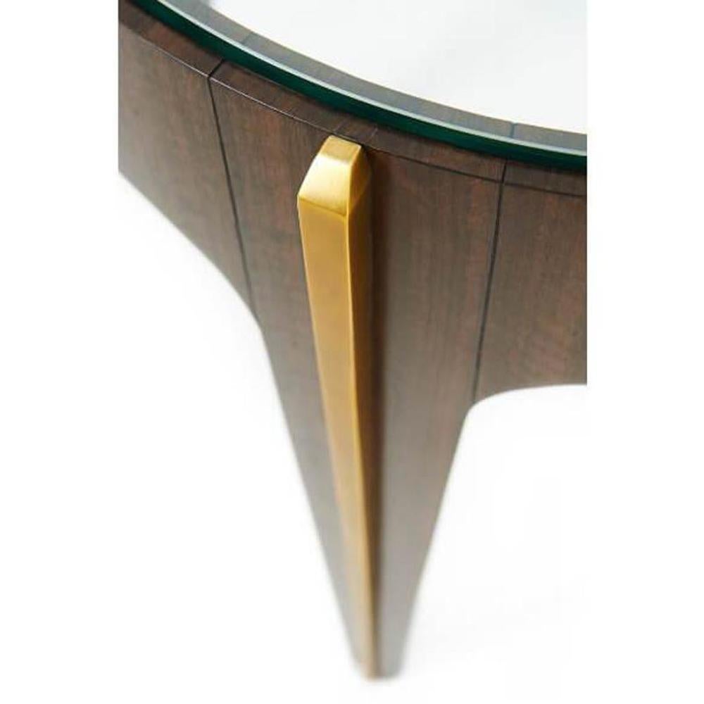 An Art Deco lamp table with fumed Eucalyptus veneered and brass mounted lamp table, the circular tempered glass inset top within a bold veneered frieze, the gently tapered legs with bold brass moldings. Inspired by an Art Deco