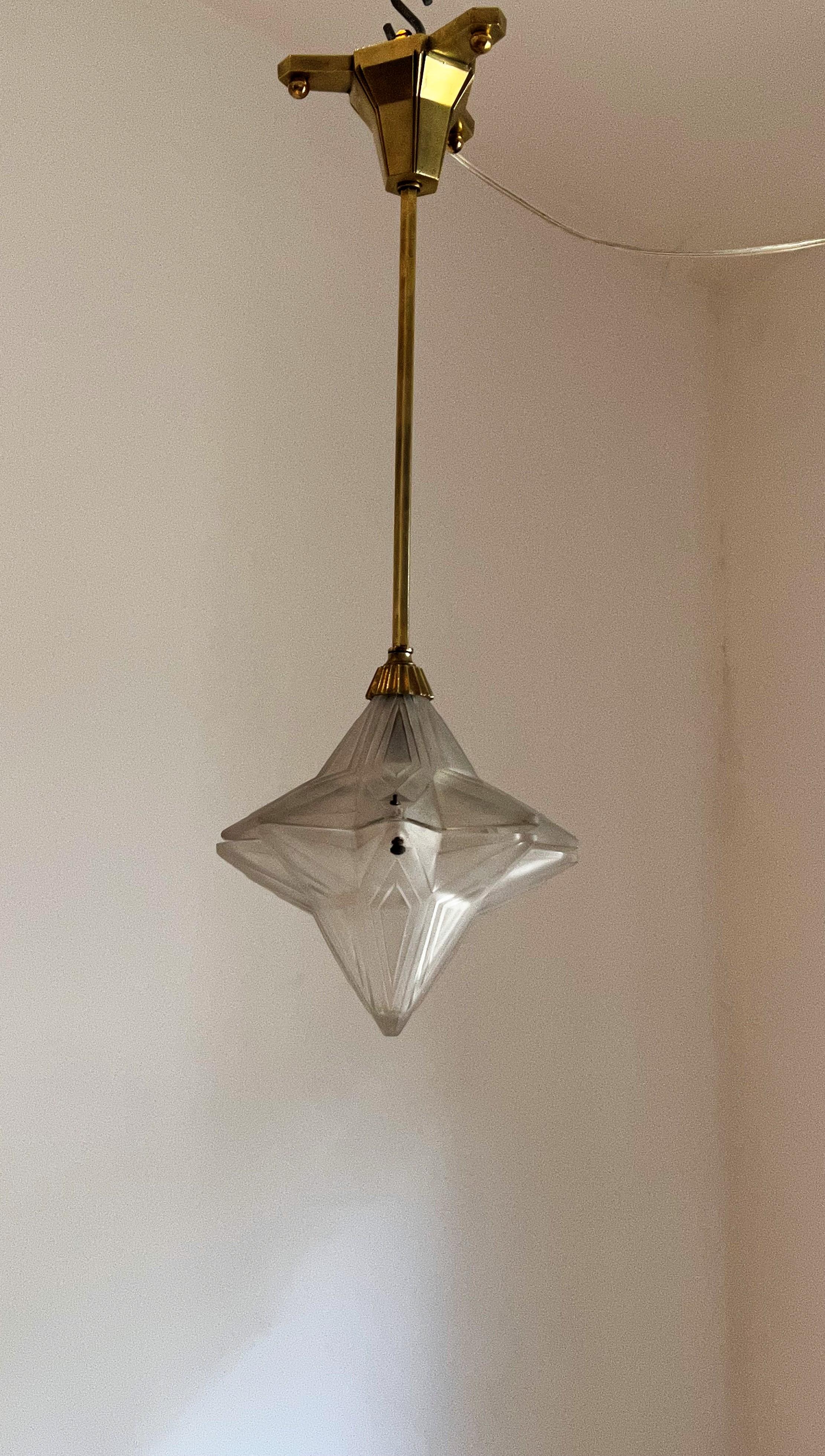 Magnifique lanterne d'entrée Art Déco de Genet Michon fabriquée en laiton et verre pressé en forme d'étoile.
Le verre est signé, il y a quelques petits éclats qui ne se voient pas une fois accroché.
Cette lanterne peut être suspendue ou montée à ras