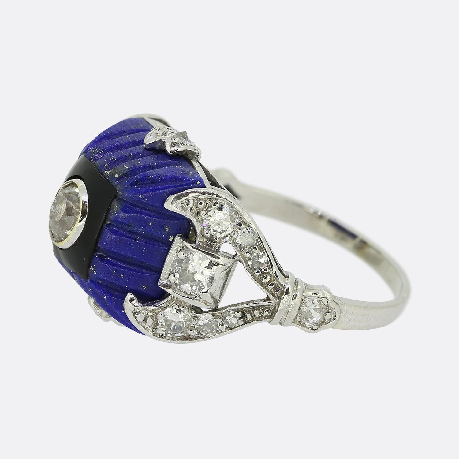 Here we have a wonderfully unique ring from a time when the Art Deco style was at the height of design. A square domed shaped lapis lazuli with vertical engravings dominates the face and acts as the backdrop for this proud piece. This impressive