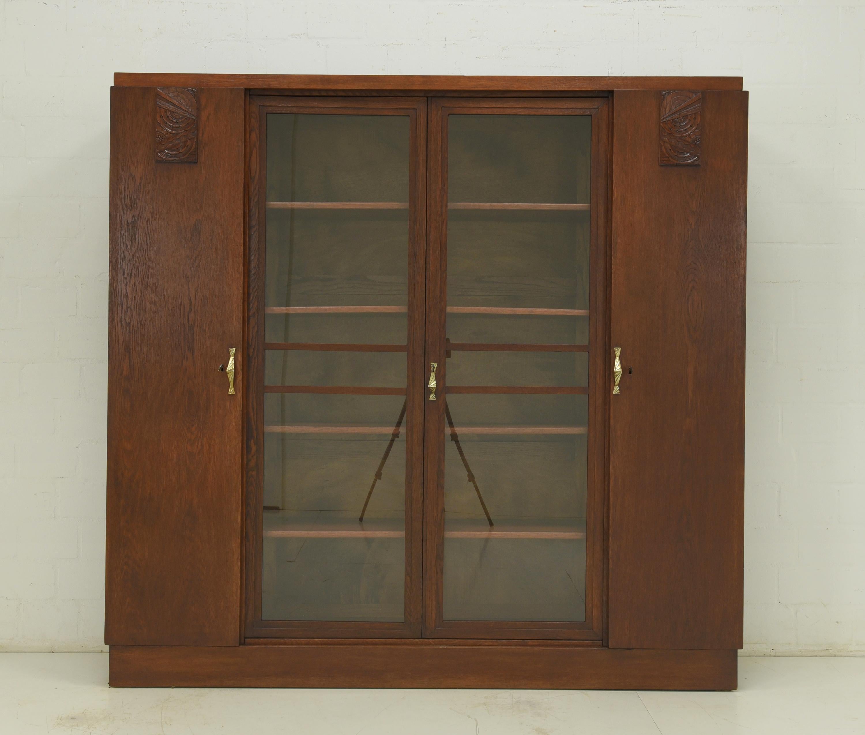 Large bookcase restored Art Deco circa 1925 oak display cabinet

Features:
Solid oak shelves, height adjustable
Original fittings
Original rod locks
Subtle, abstract carving applications
Reduced, geometric Art Deco design
Timeless