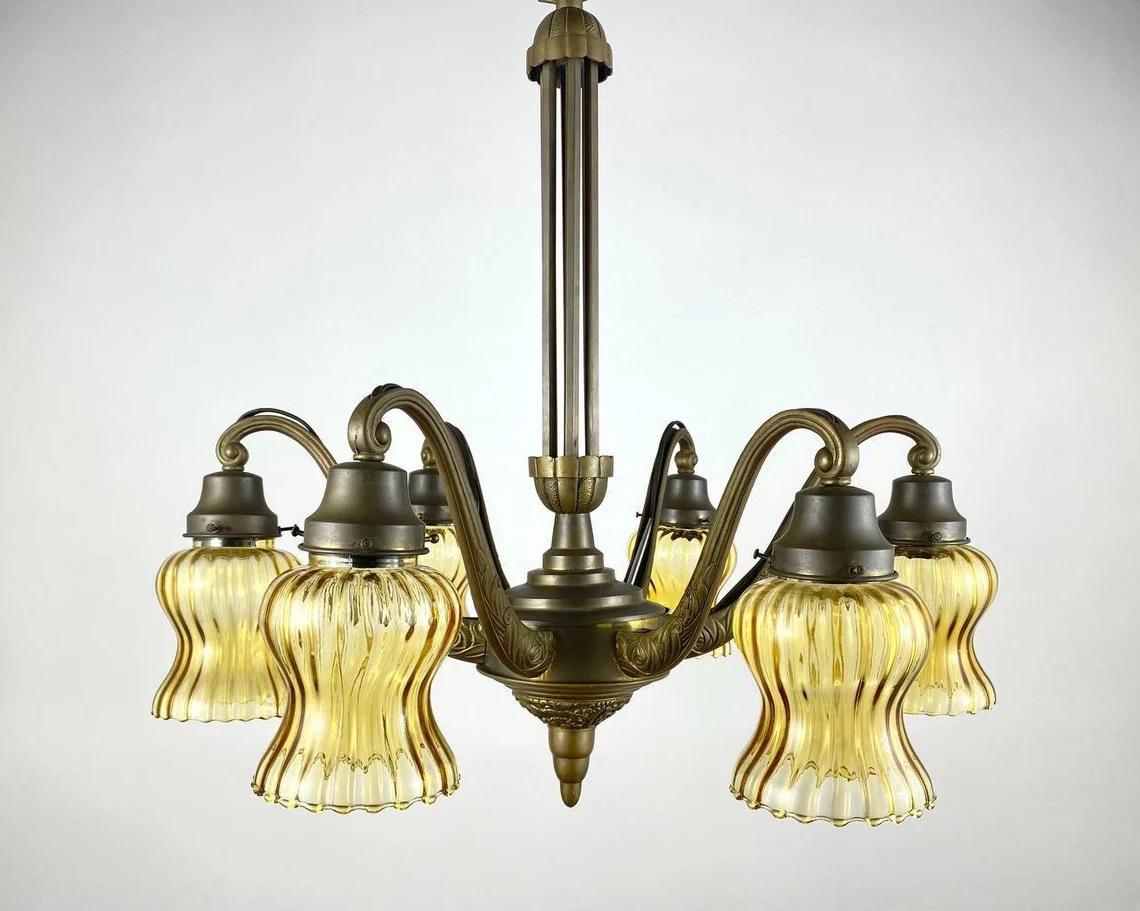 Large Antique Art Deco Chandelier. 1920. Belgium.

Antique Chandelier is a wonderful example of classic style in a modern interior. Flower shades with wavy edges are made of colored glass and decorated with facets. They gently dim the light flux,