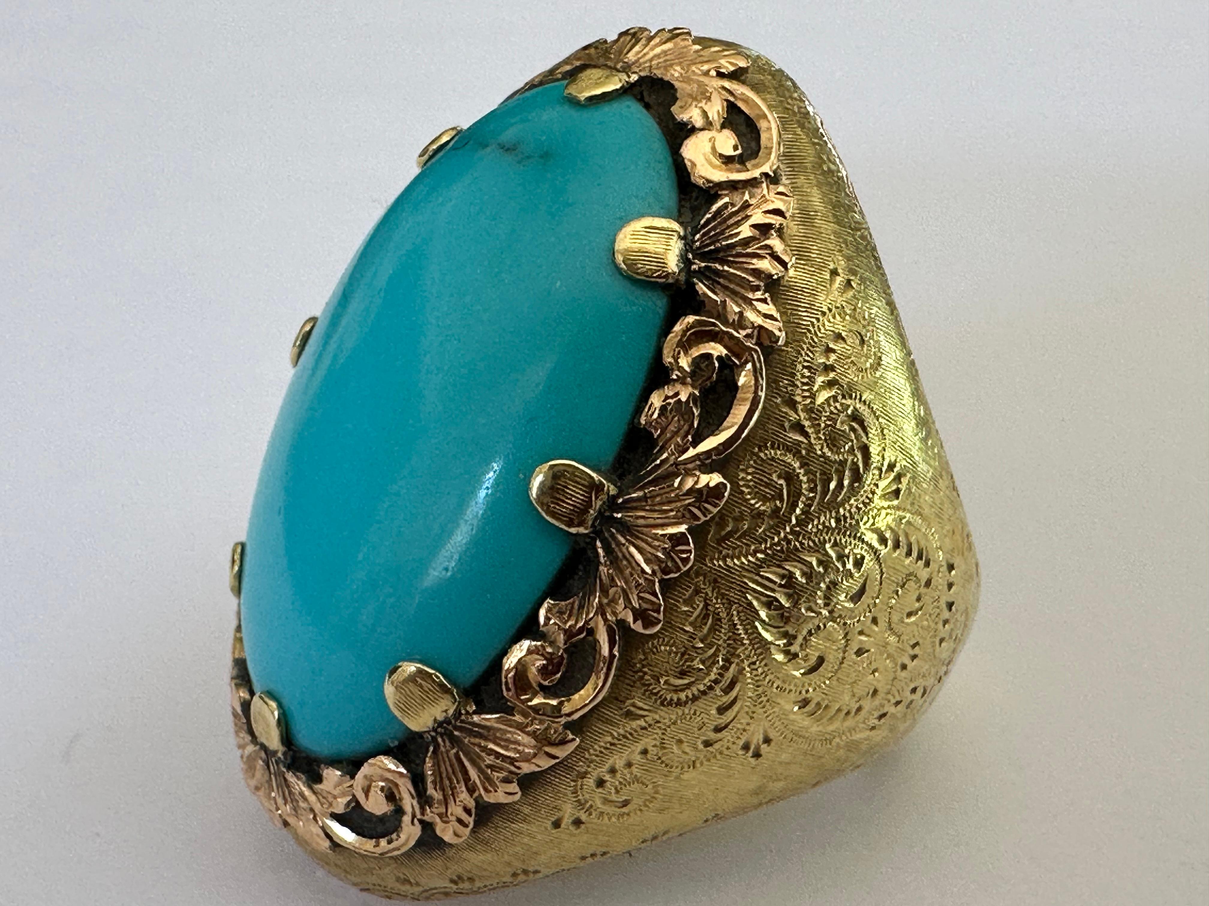 This striking antique cocktail ring features a large natural oval turquoise stone measuring approximately 23.5 X 15.5mm crafted in 18K yellow and rose gold hand-engraved with an intricate floral motif. The captivating color of the turquoise and the