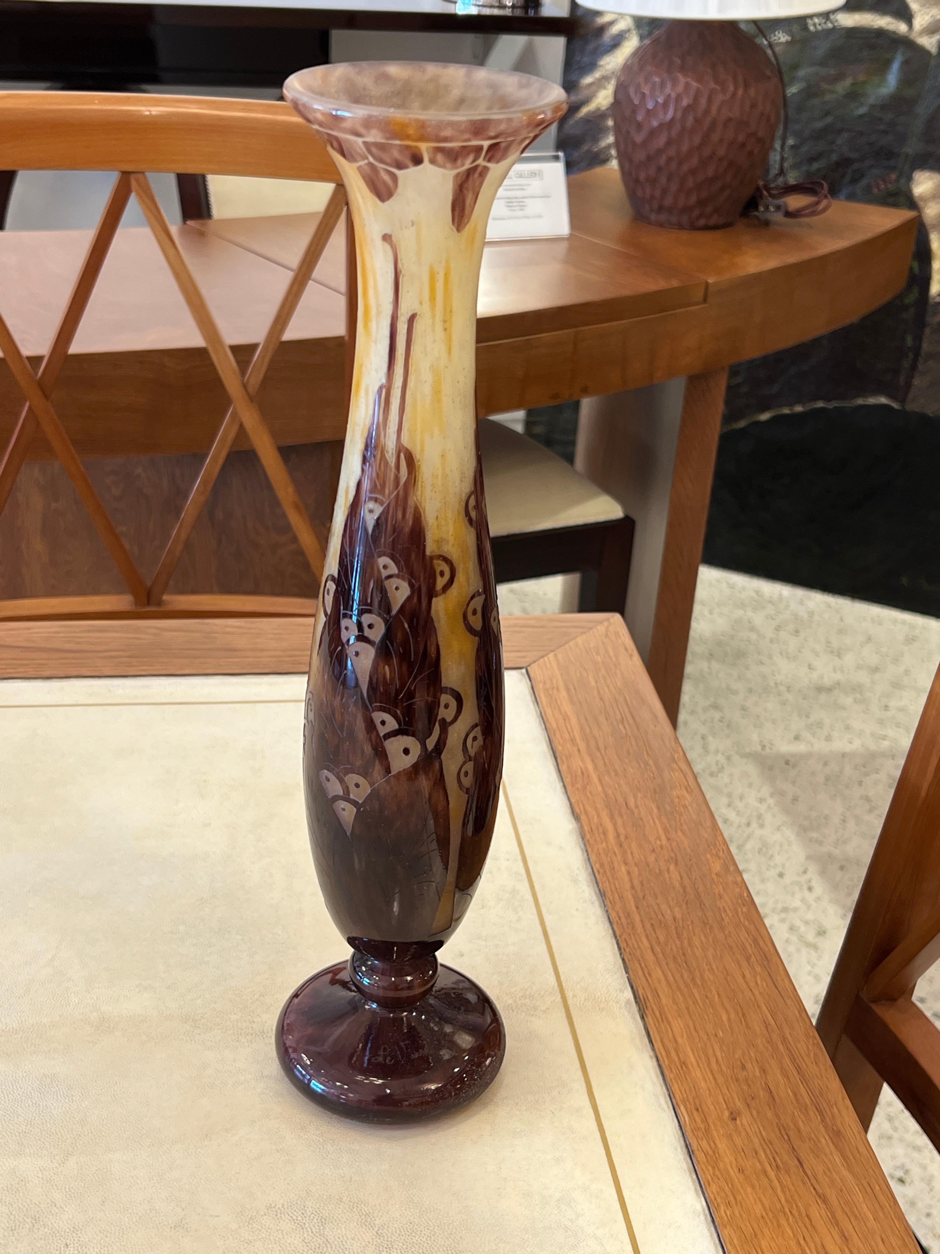 A cylindrical-shaped vase in Mottled Opalescent White, Yellow and Orange glass overlaid with Violet color acid-etched pattern.  The floral pattern is from the Lauriers serie of Le Verre Français. 
Signature: Le Verre Francais.

Charles Schneider was