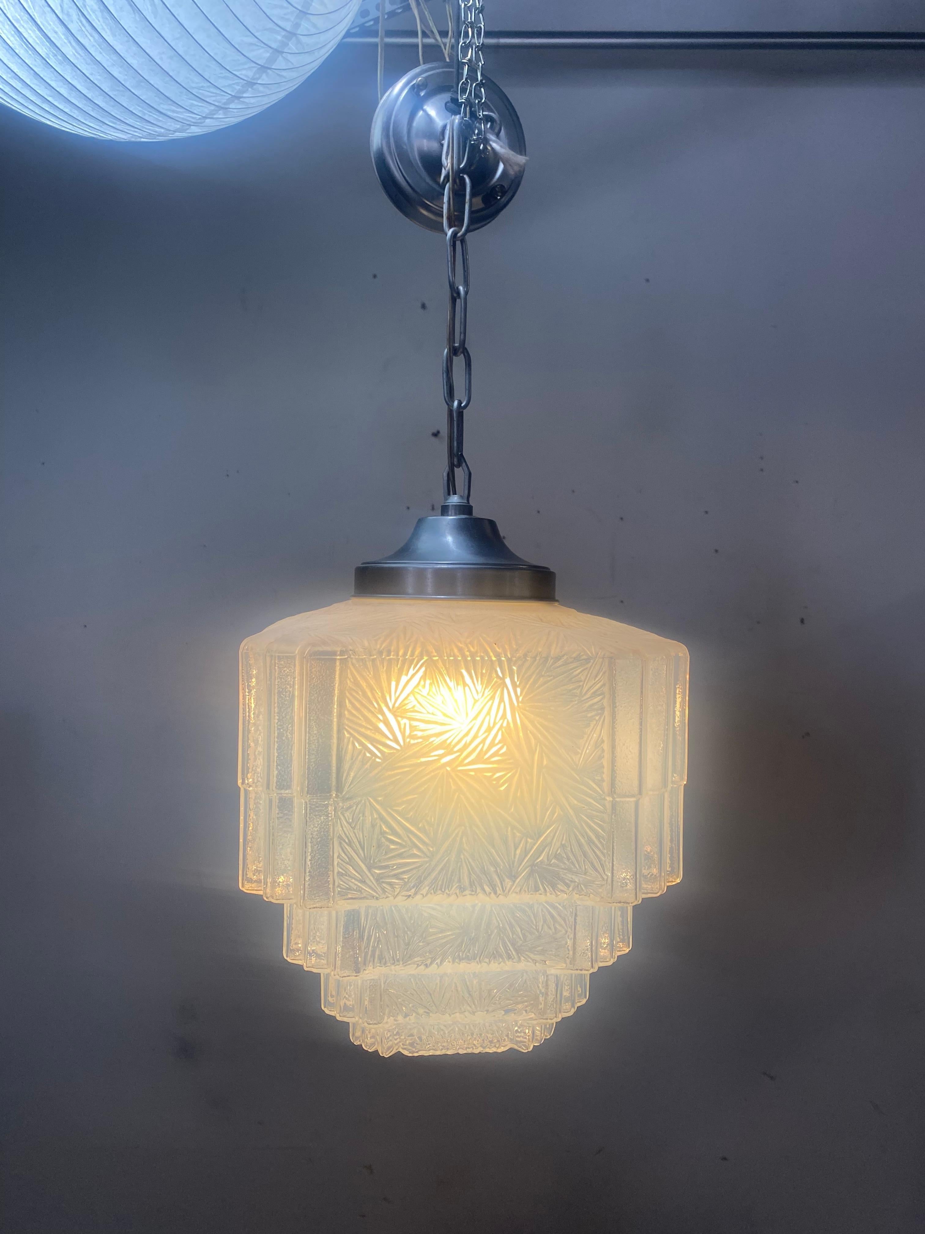 Art Deco pendant light features a layer cake, ribbed pattern opaline glass shade on a chrome chain with canopy. The shade measures 12 diameter x 13 height.