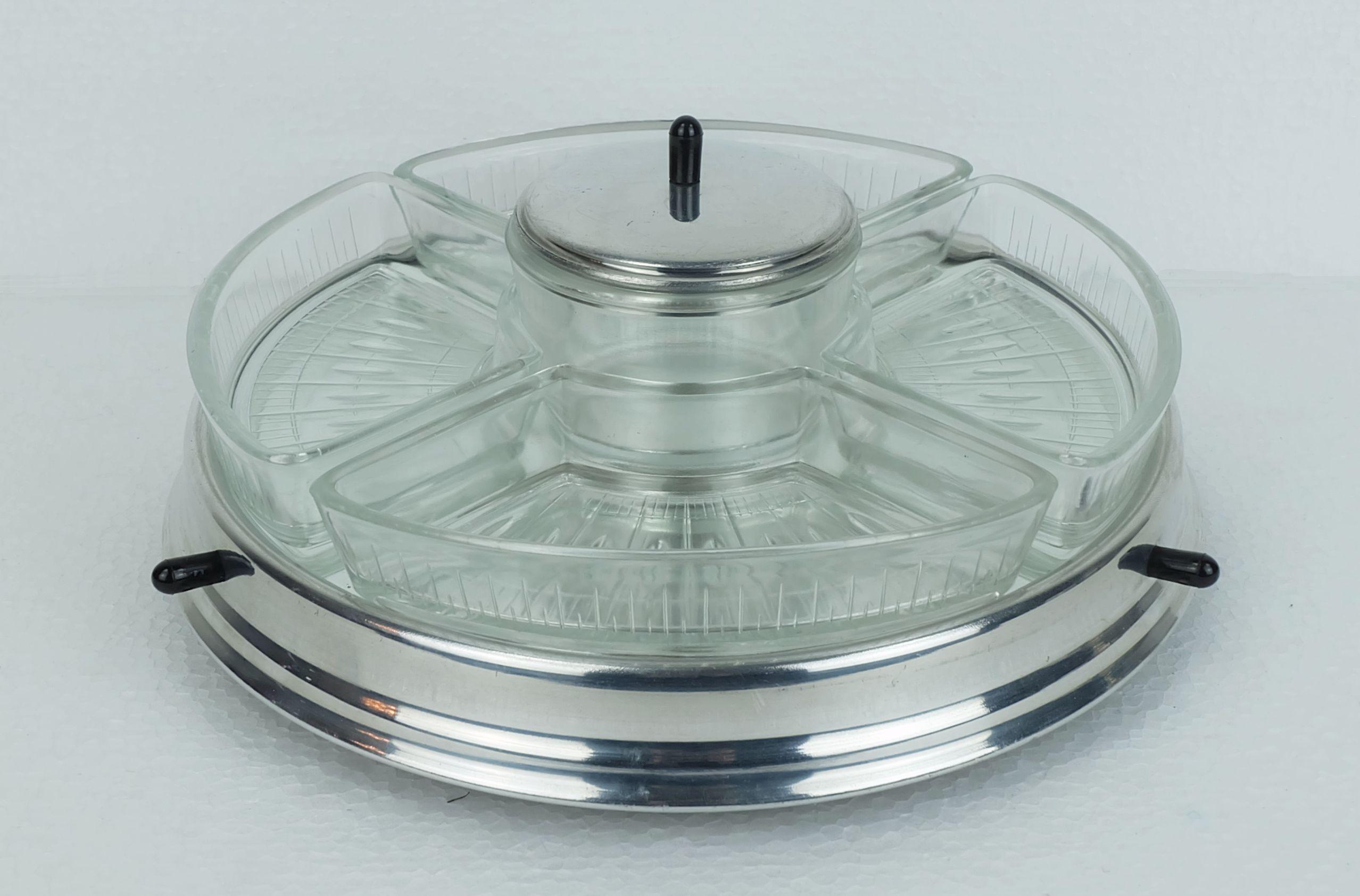Un superbe service à sauce art déco. Il s'agit d'un ensemble de 5 pièces composé de bols en verre pressé et d'un pot à couvercle disposés sur un plateau rotatif avec une surface miroir, un bord et une base en aluminium. Le couvercle du pot est