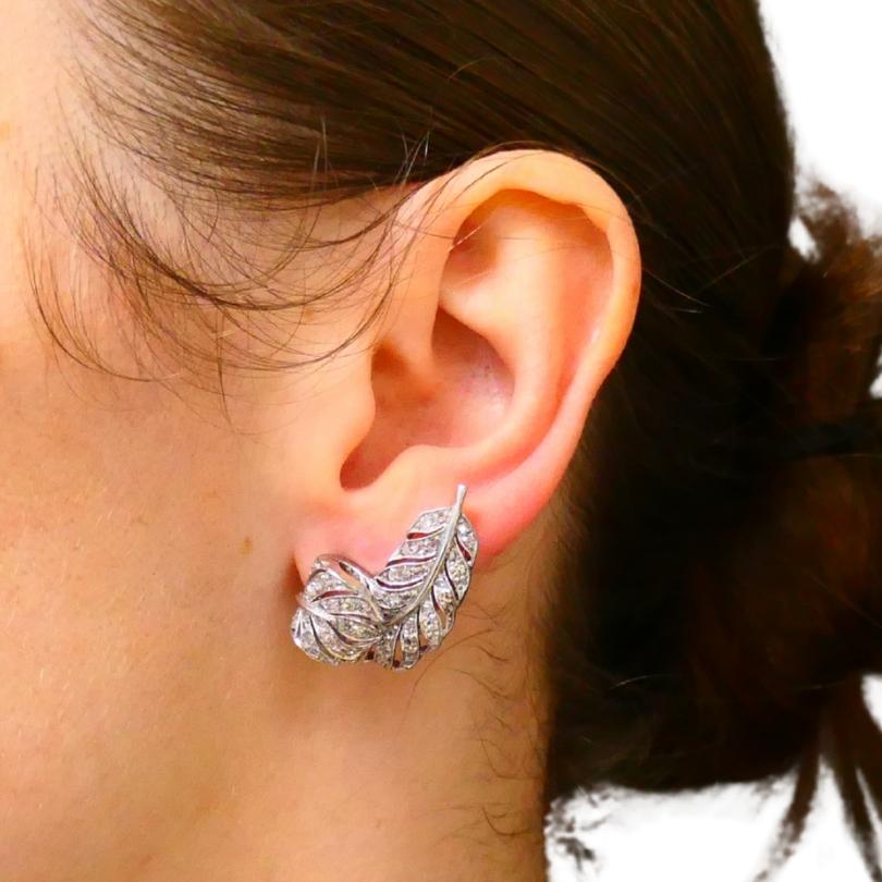 A gorgeous pair of Art Deco leaf shaped earrings, crafted of platinum, featuring diamonds. 
The earrings’ design follows the natural curves of a leaf, with delicate veins formed by platinum lines weaving through the surface. The diamonds are set