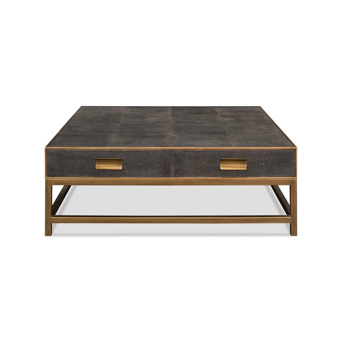 Crafted from wood with a shagreen embossed leather wrapped top, this square coffee table is finished with gold trim and hardware. With two drawers and raised on cube-form base with stretchers. 

The low-profile design makes it ideal for a functional
