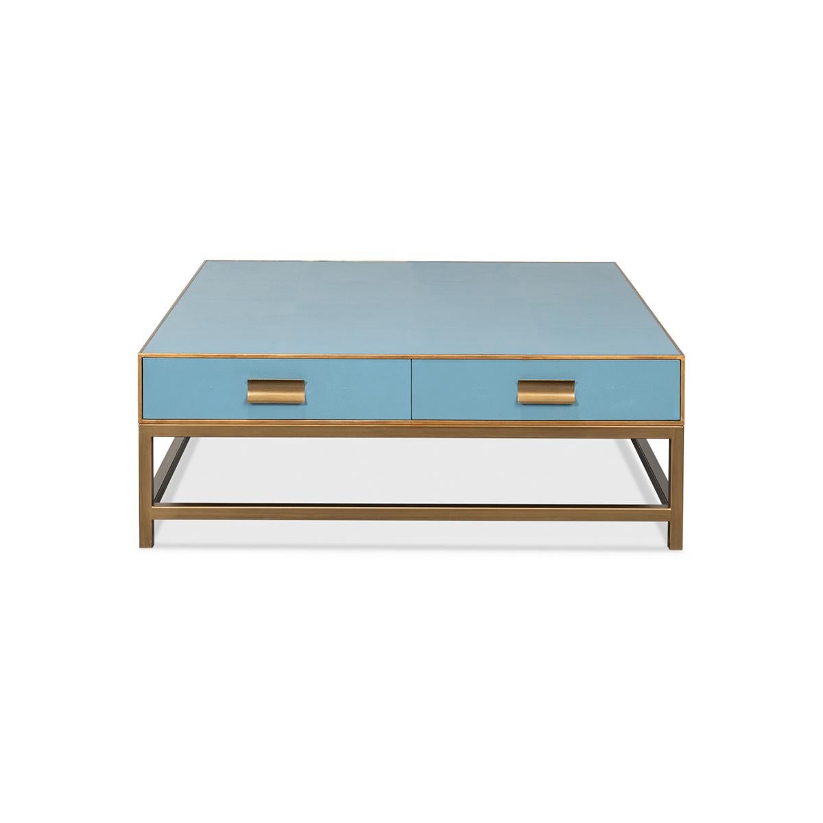 Crafted from wood with a shagreen embossed leather wrapped top, this square coffee table is finished with gold trim and hardware. With two drawers and raised on cube-form base with stretchers. The low-profile design makes it ideal for a functional