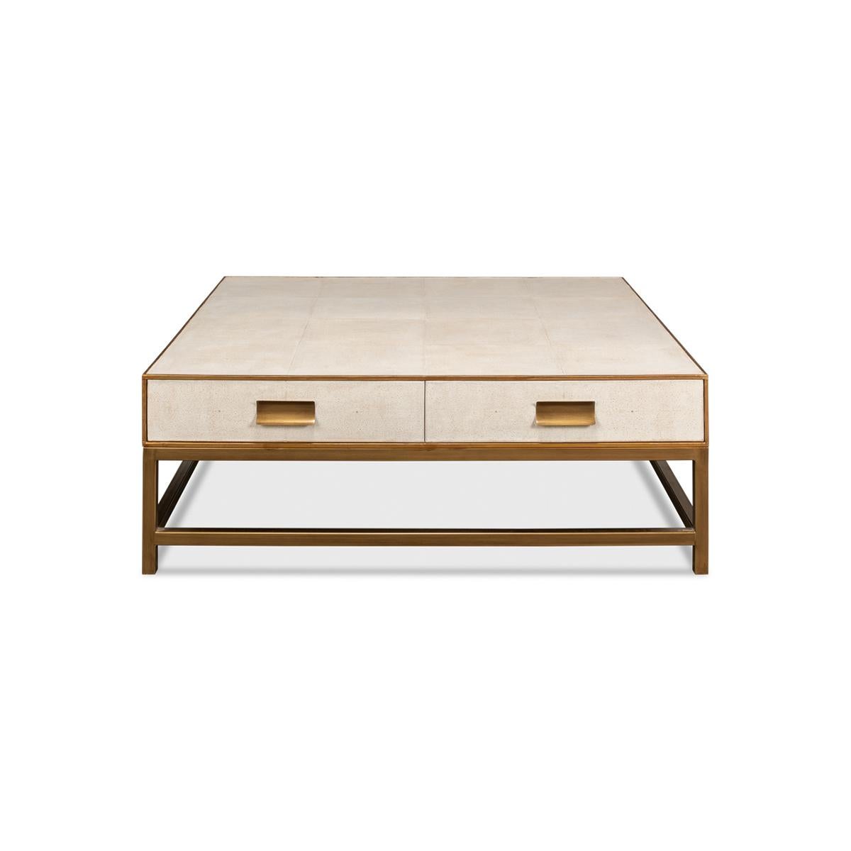 Crafted from wood with a shagreen embossed leather wrapped top, this square coffee table is finished with gold trim and hardware. With two drawers and raised on cube-form base with stretchers. 

The low-profile design makes it ideal for a functional