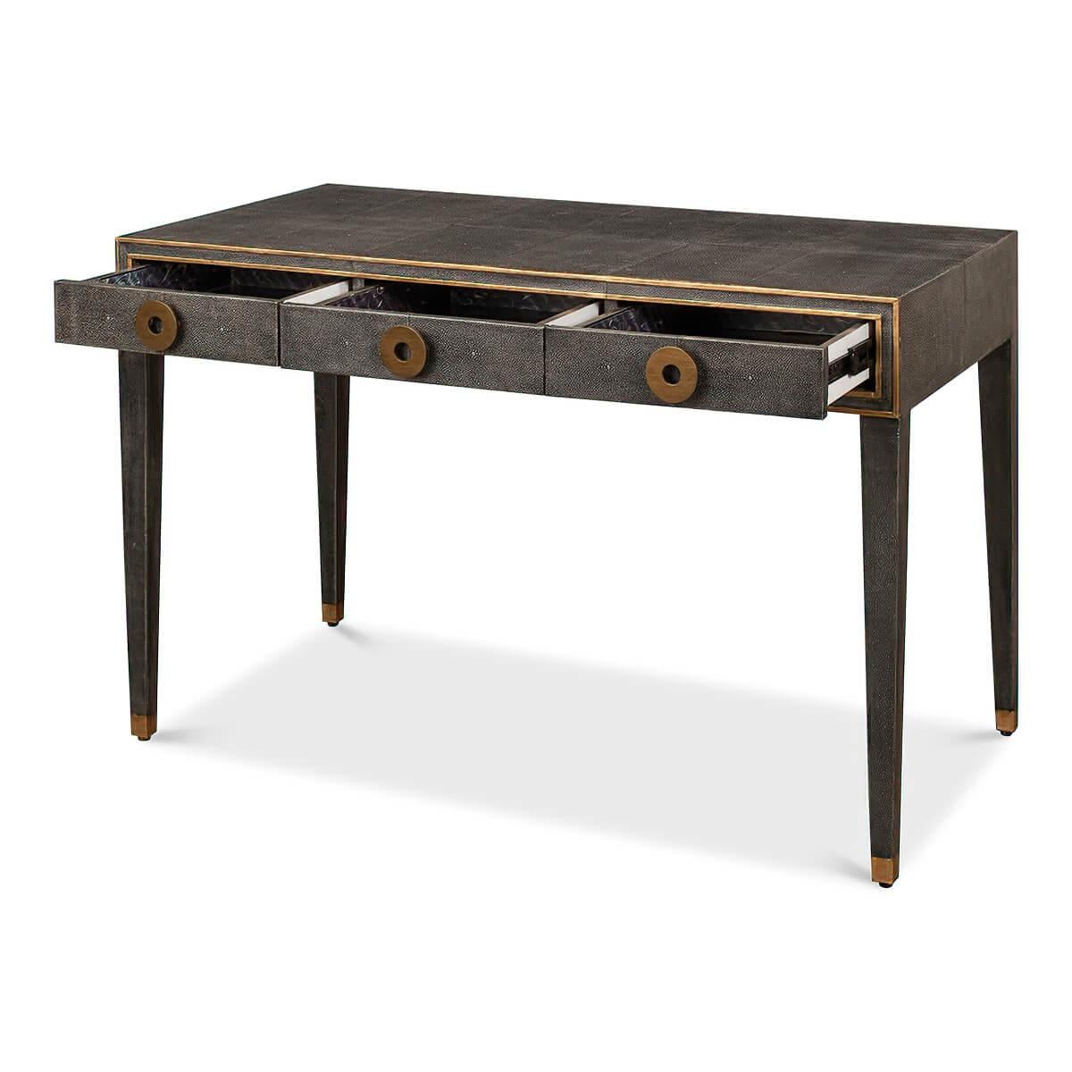 A French Art Deco style shagreen embossed leather desk in a dark antiqued grey. With gilded highlight trim, three frieze drawers with modern round pulls, and raised on square tapered legs.

Dimensions: 49