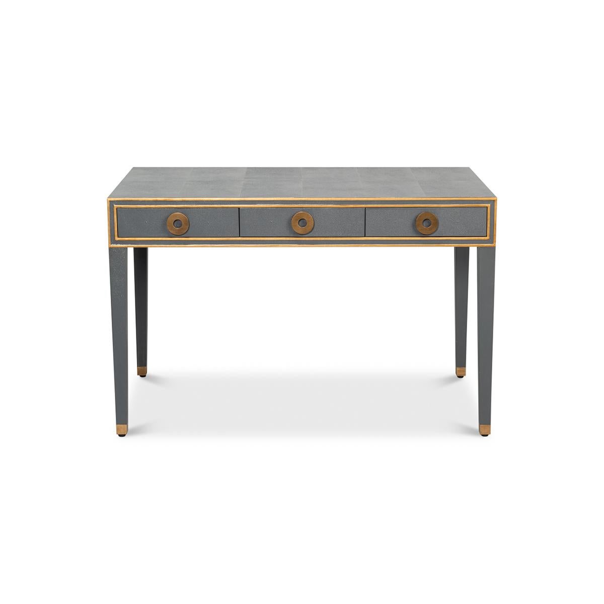 A French Art Deco style shagreen embossed leather desk in a rich pewter grey. With gilded highlight trim, three frieze drawers with modern round pulls, and raised on square tapered legs.

Dimensions: 48