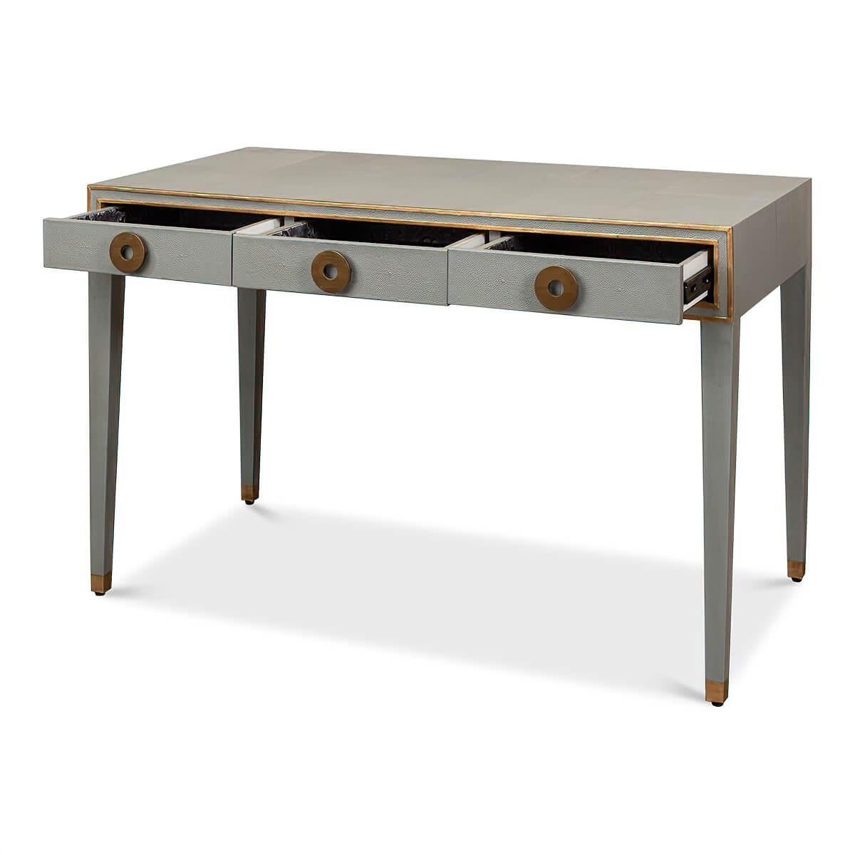 A French Art Deco style shagreen embossed leather desk in a light grey. With gilded highlight trim, three frieze drawers with modern round pulls, and raised on square tapered legs.

Dimensions: 49