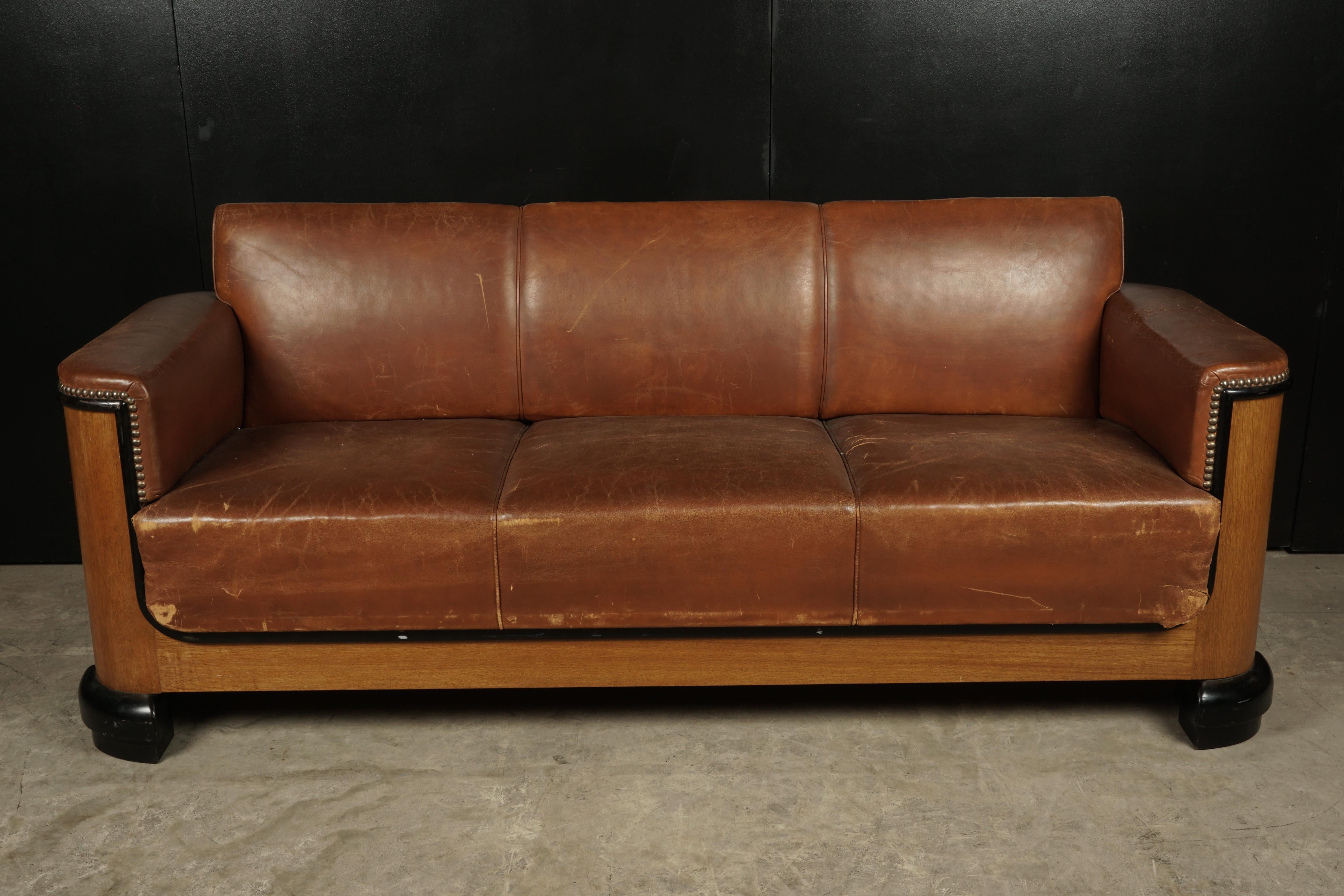 Art Deco leather sofa from Denmark, circa 1940. Original brown leather upholstery. Sides and base of oak with black lacquered feet.