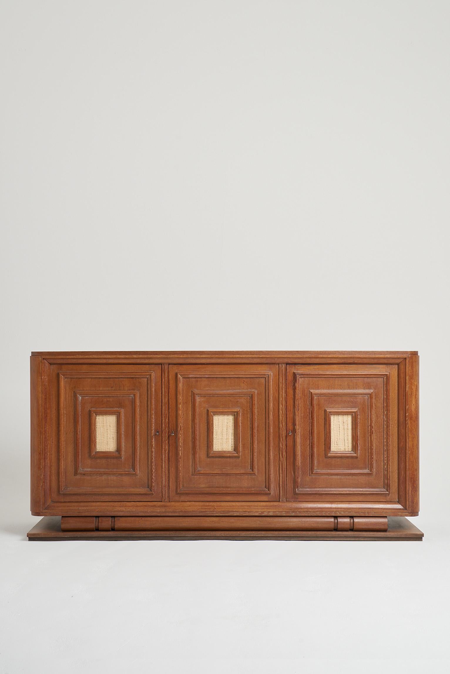 An Art Deco limed oak three-door sideboard, with later raffia cartouches.
France, Circa 1940.