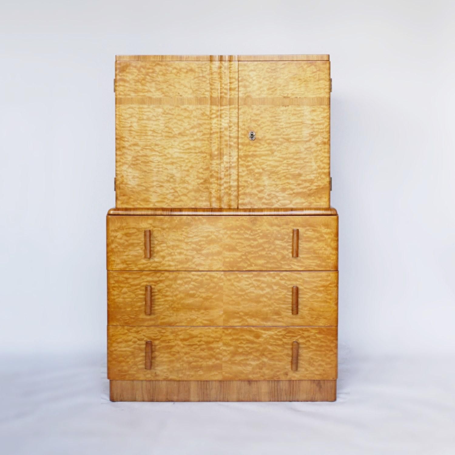 An Art Deco linen cabinet. Burr satin birch veneered on solid mahogany with figured walnut banding and handles. Three lower drawers with upper a-symmetrical upper two door cabinet.

Dimensions: H 126cm, W 835cm, D 46cm 

Origin: English

Date: