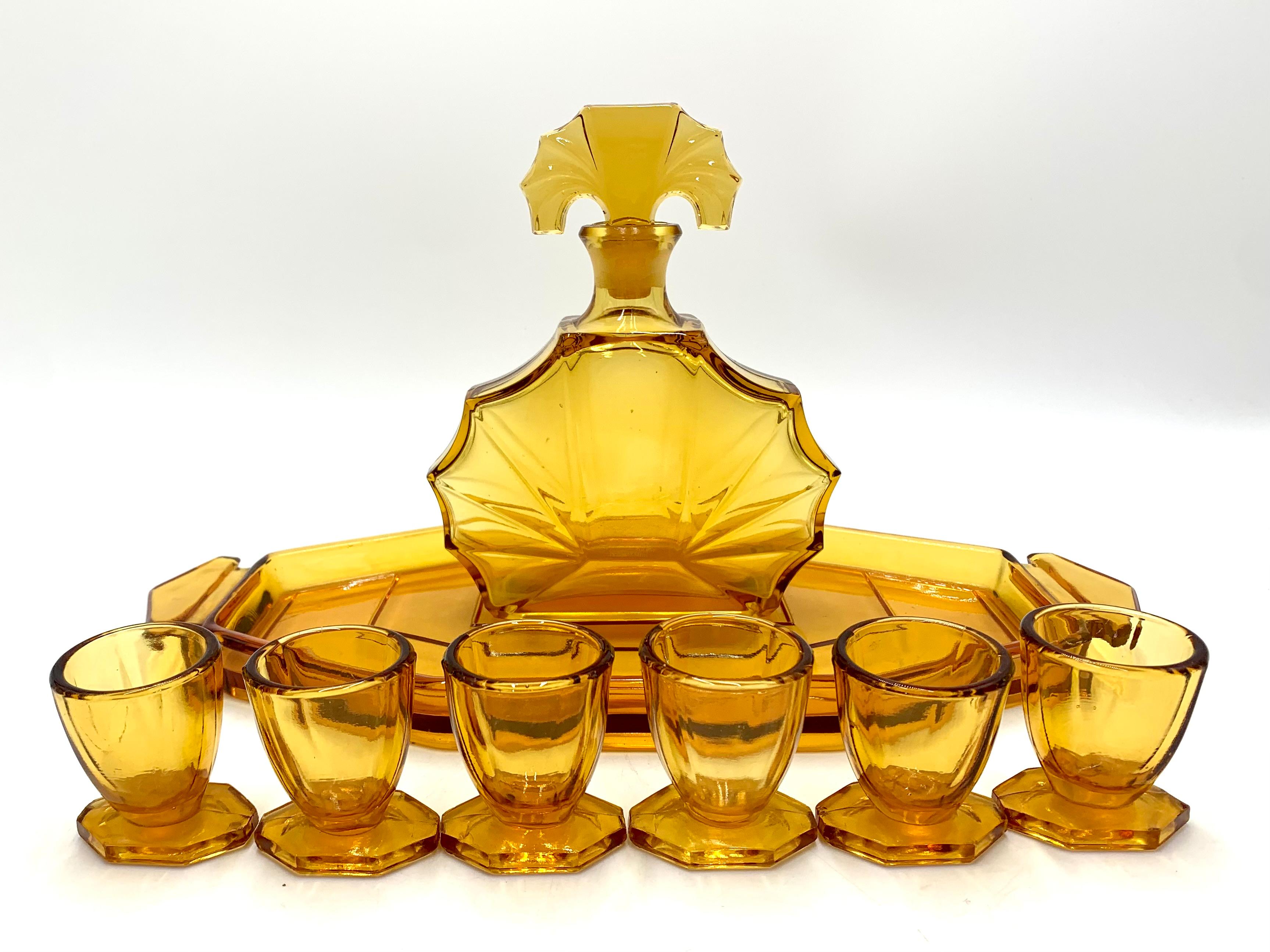 Amber glass liqueur set in the Art Deco style, consisting of a tray, a decanter and 6 glasses.

Produced in the Czech Republic by Huta Hermanova in the 1930s.

Very good condition, one glass has a broken stem on one side (shown in the