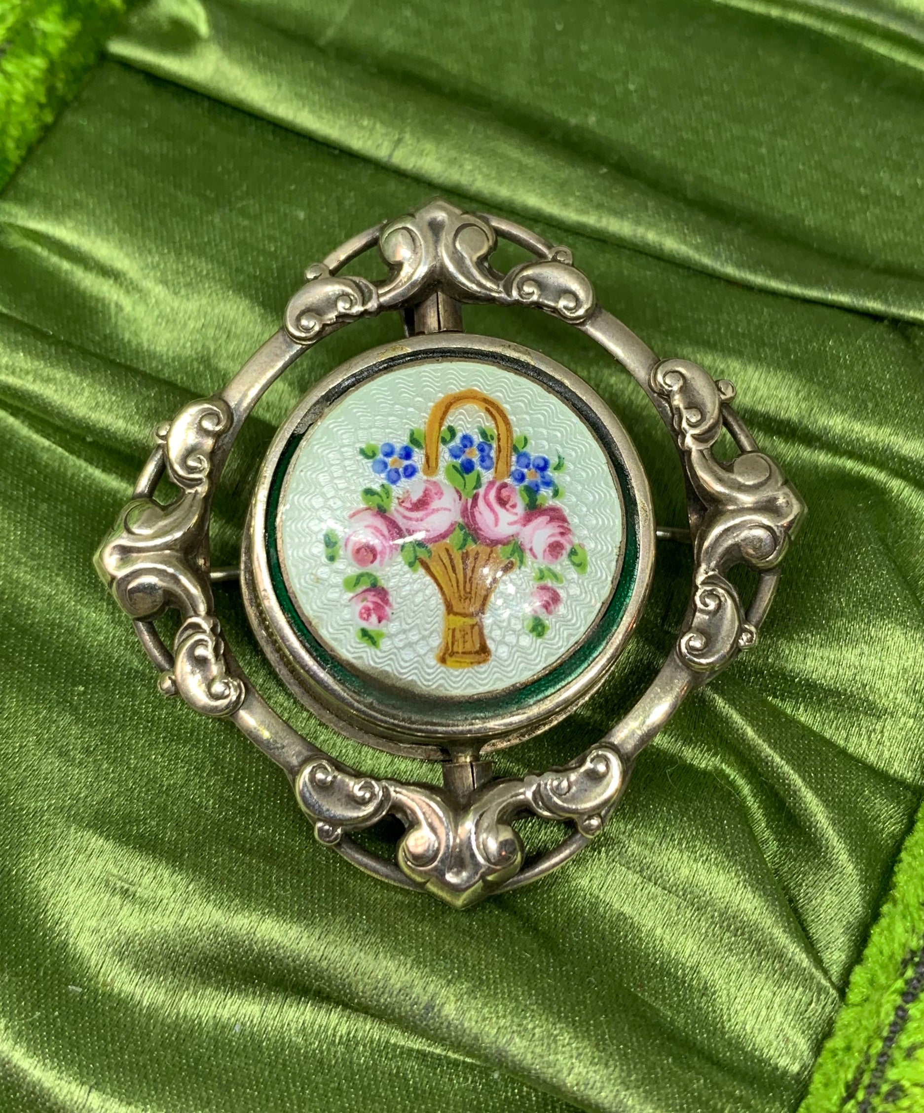 This is a wonderful antique Edwardian - Art Deco Locket Pendant or Brooch with a gorgeous Guilloche Enamel flower basket motif on a delicate pale blue-green Guilloche Enamel background over Sterling Silver.  The locket portion is on a swivel