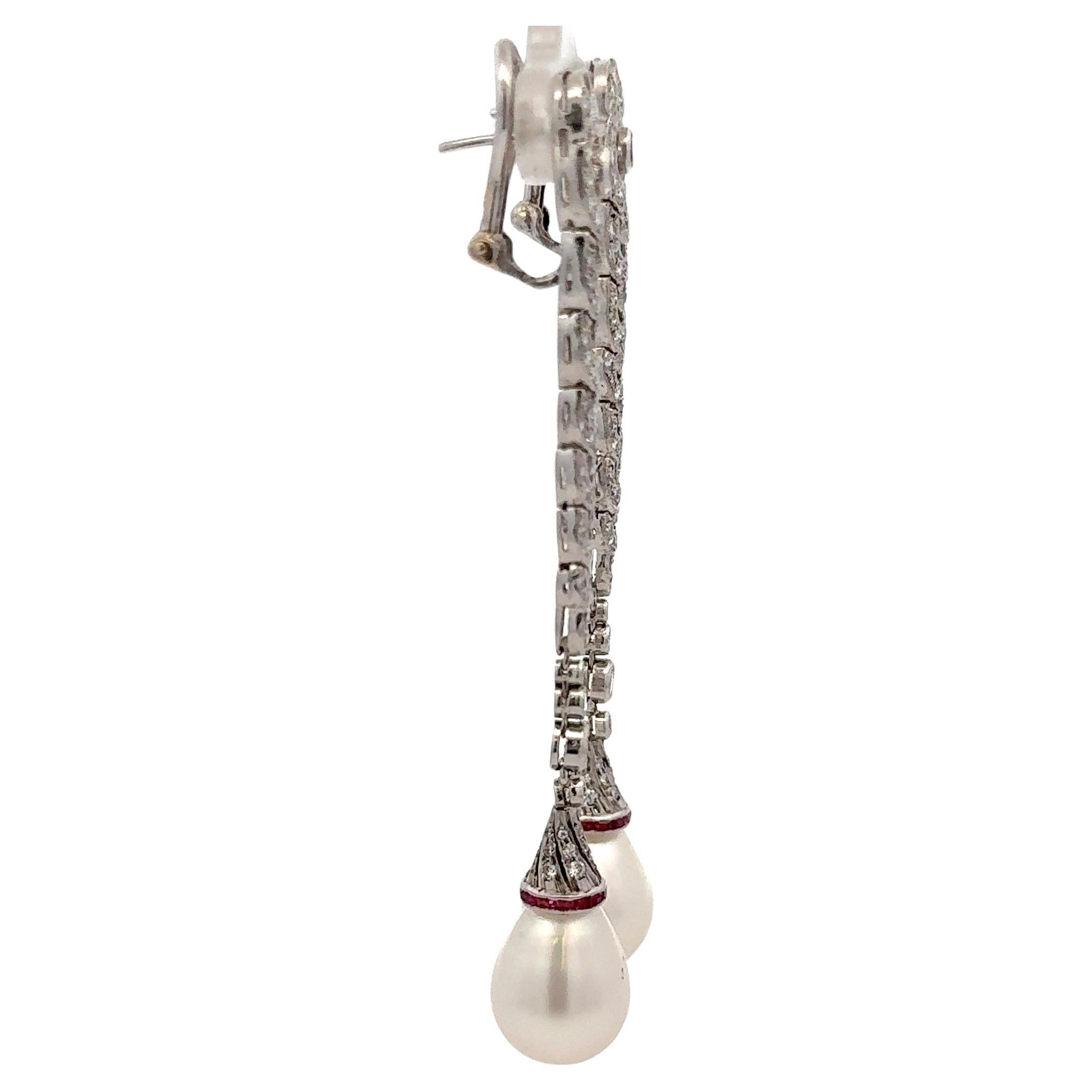 Art Deco drop earrings featuring round diamonds weighing approximately 1.50 Carats and touches of red Rubies, in 18 karat white gold. 
Pearl 13-14 mm