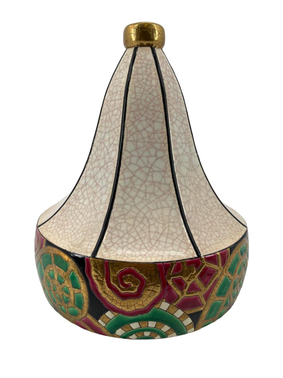 Un grand vase Art Déco en céramique, de forme polygonale, décoré d'une glaçure craquelée crème et d'émaux aux couleurs vives, avec un freize cloisonné de frondes de fougères stylisées. Contre-titre imprimé 