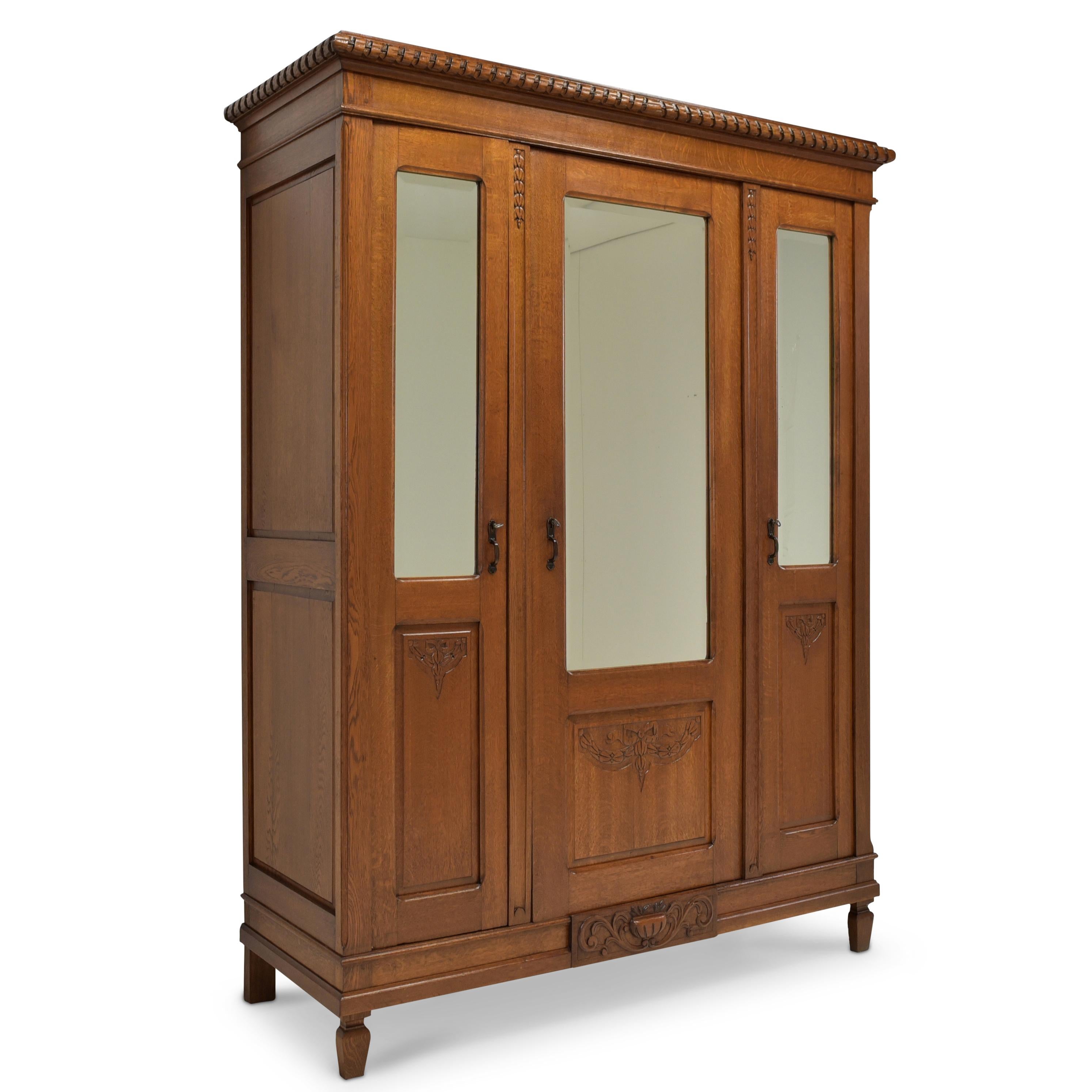 Hallway wardrobe restored Art Deco / Louis XVI 1920 oak wardrobe

Features:
Three-door model with three mirrors and clothes rail
High quality
Cassette fillings
Original faceted mirror
Straight basic form with carved decorations
Attractive,