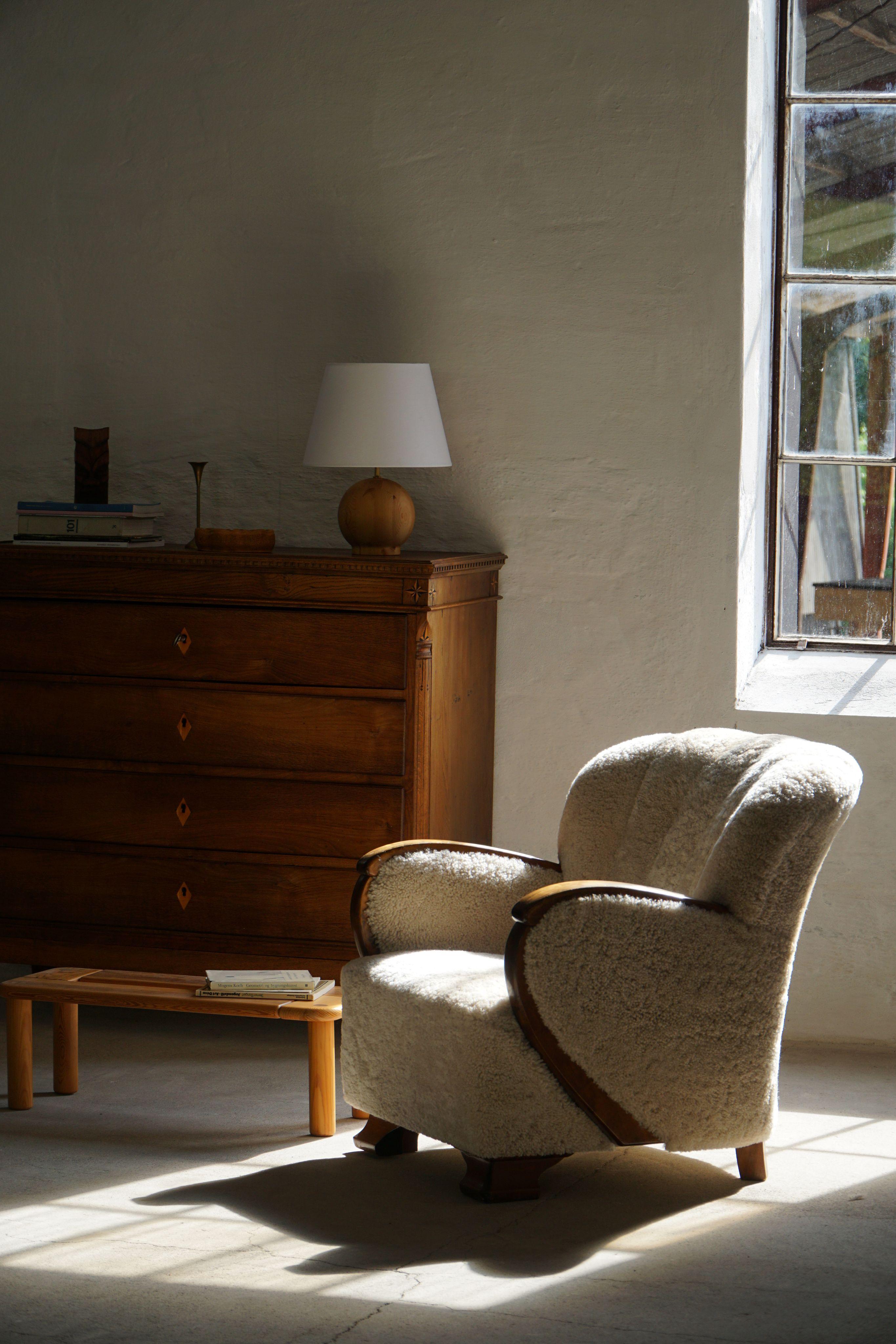 An elegant curved Art Deco lounge chair with birch armrests, crafted in the 1930s by a skilled Danish cabinetmaker. The warm, expressive grain of the wood adds a refined touch to the chair’s sculptural form. Recently reupholstered in luxurious,
