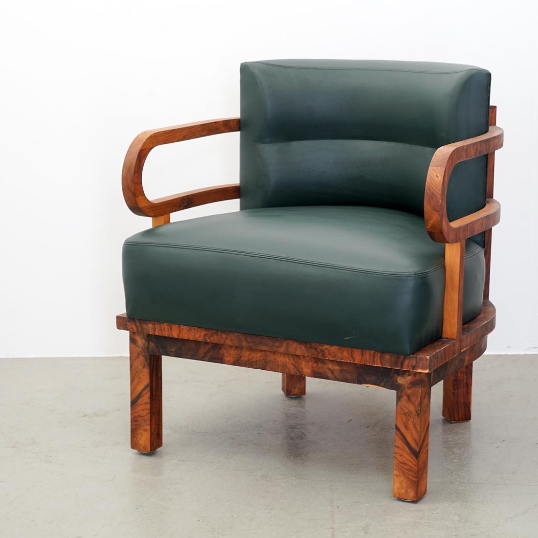 The very characterful and elegant original Art Deco armchair impresses with its rounded wooden armrests, its ergonomic backrest and its materials wood and leather. The upholstery was redone in 2015 with a soft, fir green bioleather. The wooden base