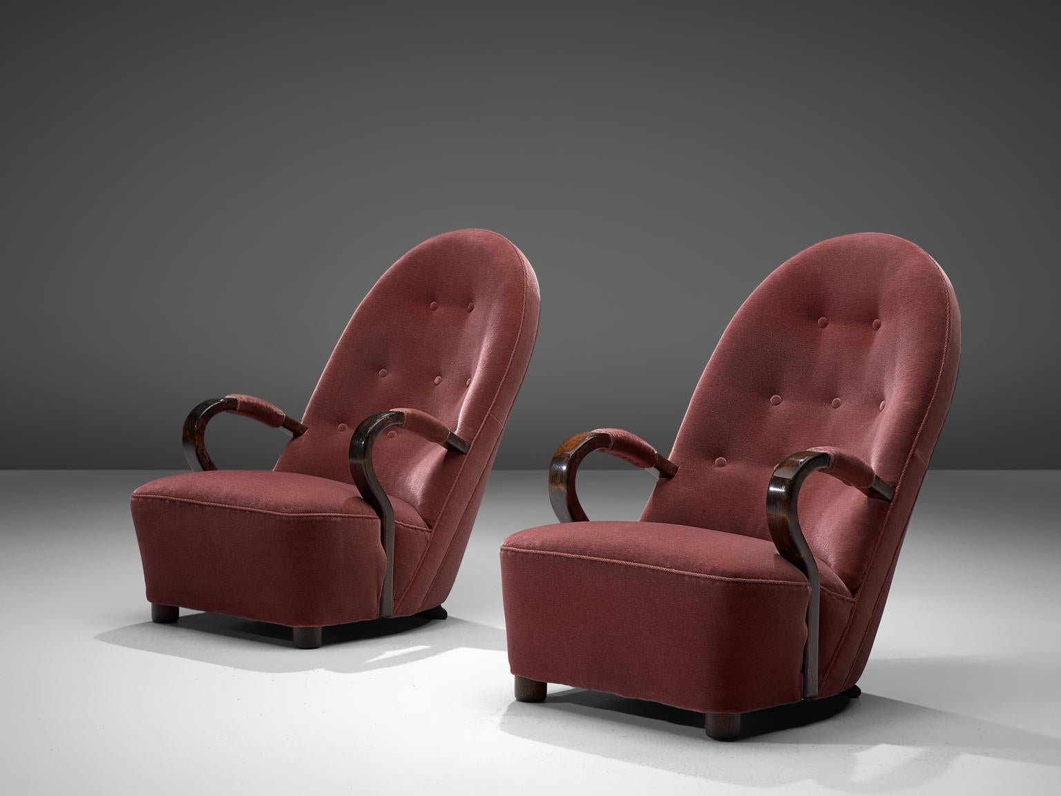 Pair of red/pink Art Deco lounge chairs, velvet and dark stained oak, France, 1930's

These Art Deco arm chairs feature a high majestic backrest with elegant, bended armrests, and a voluptuous seat. The short legs are tubes shaped made of dark
