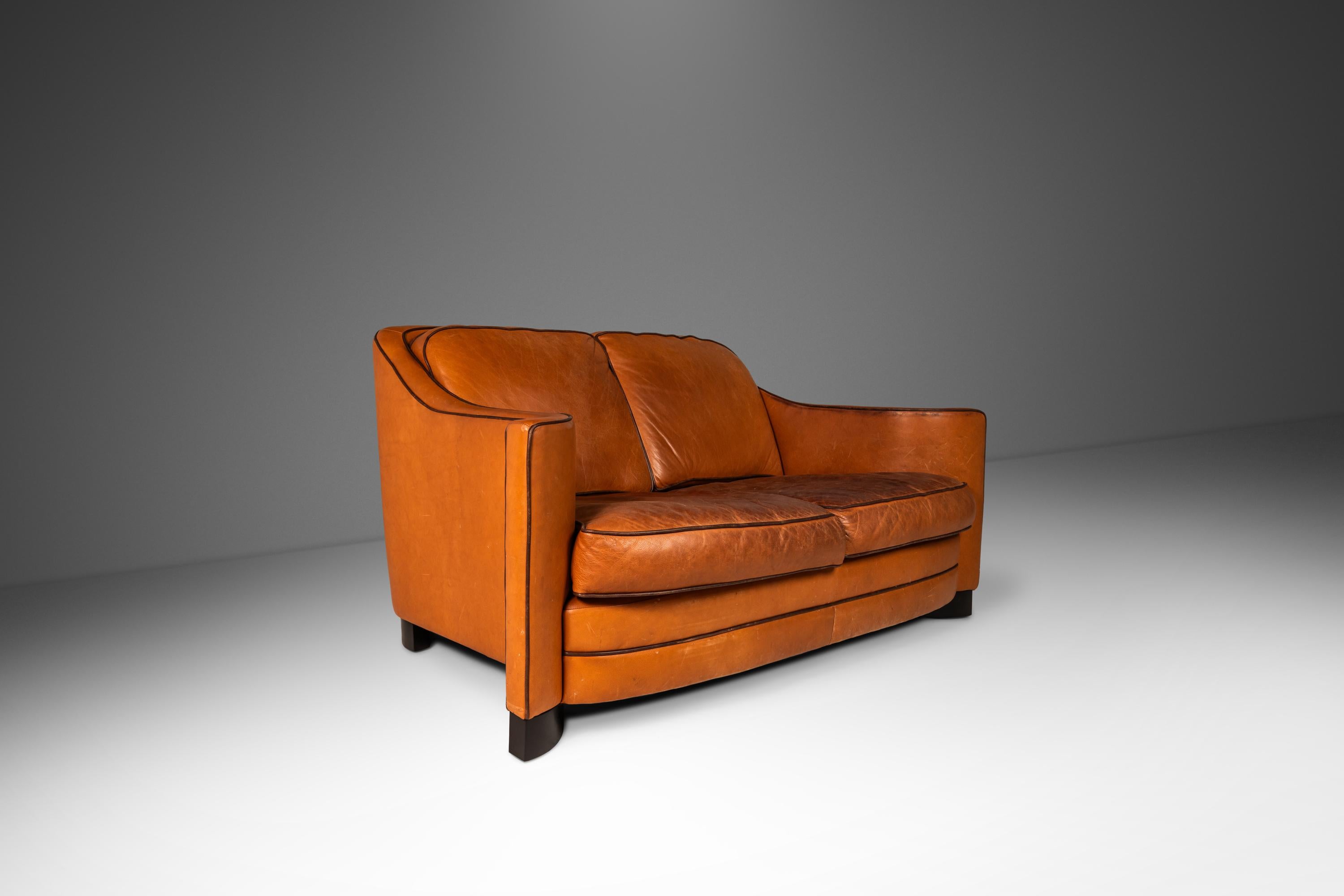 Dieses architektonisch beeindruckende und äußerst bequeme Dreisitzer-Sofa hat Designern und Sammlern gleichermaßen viel zu bieten. Mit seinen vom Art-Déco inspirierten, geschwungenen Armlehnen und den kunstvoll geschnitzten, geschwungenen Füßen