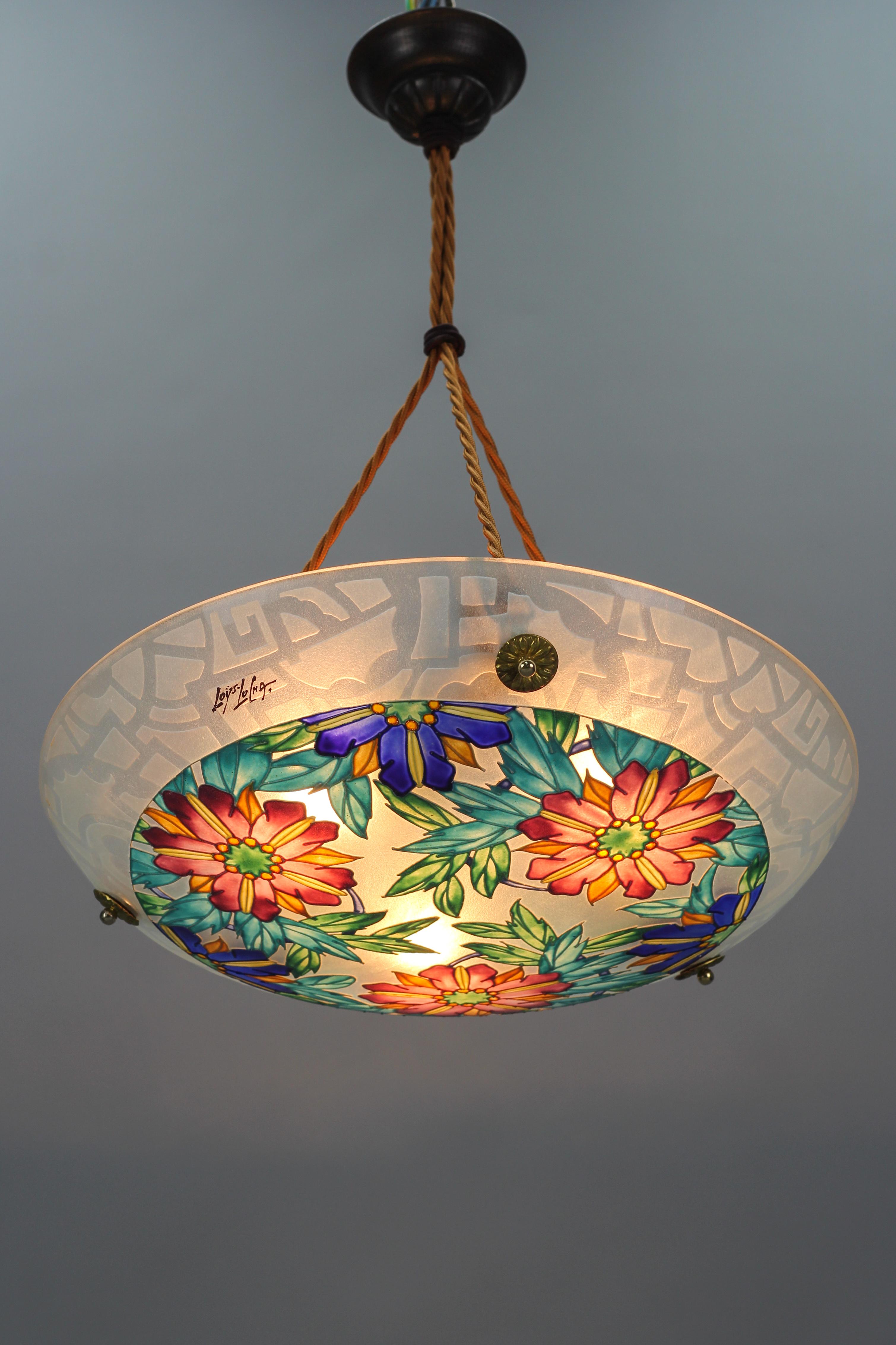 This beautiful Art Deco molded, frosted, and painted thick glass ceiling light features a floral design in purple, yellow, orange, blue, and green colors, signed “Loys Lucha”. Outer edge decorated with a geometric design. The colorful pendant light