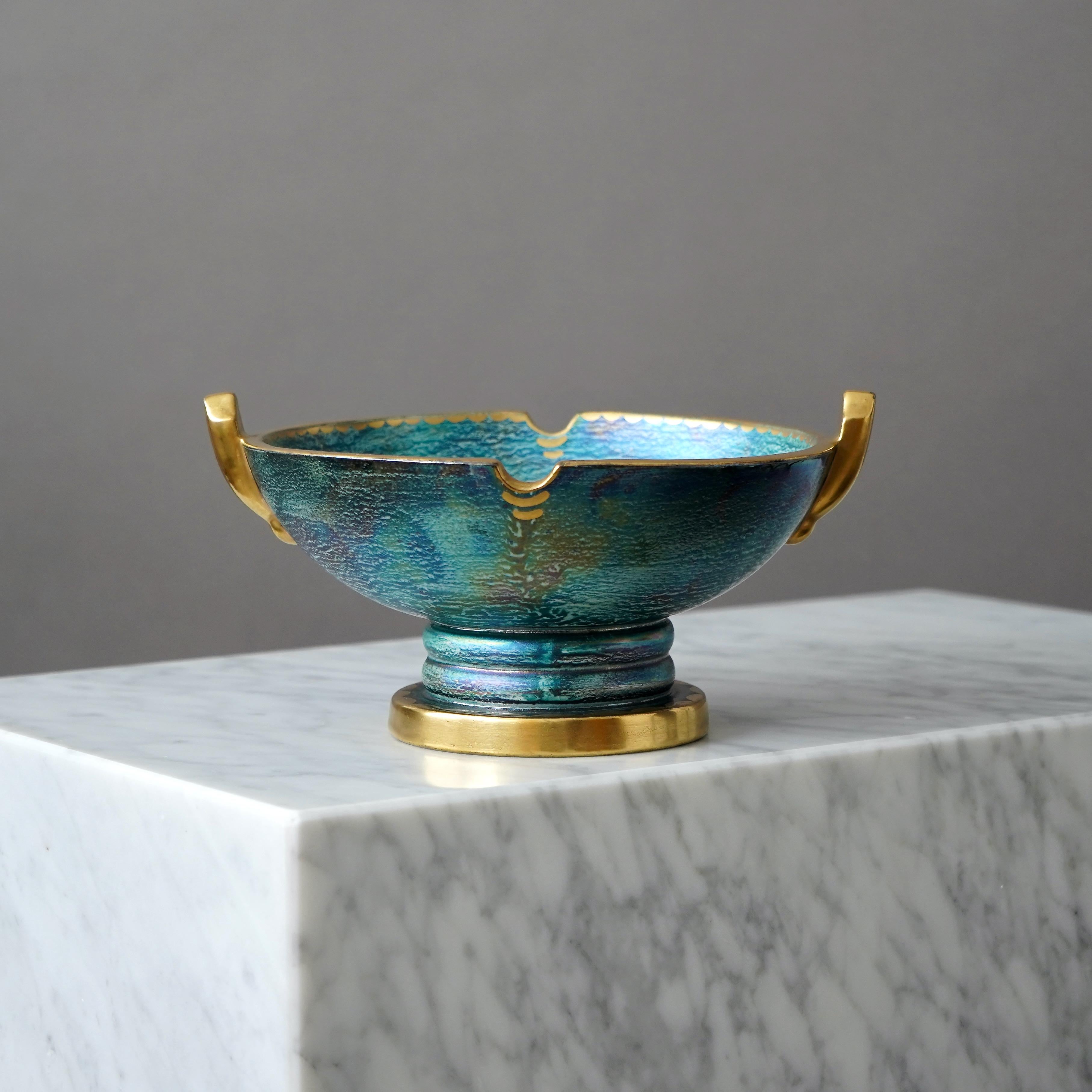 A beautiful footed bowl with amazing lustre glaze and hand painted gold details. Scandinavian Grace / Art Deco.
Made by Josef Ekberg at Gustavsberg, Sweden, 1920s.

Great condition. 
Signed 'J.E.' and stamped with makers mark.

JOSEF EKBERG