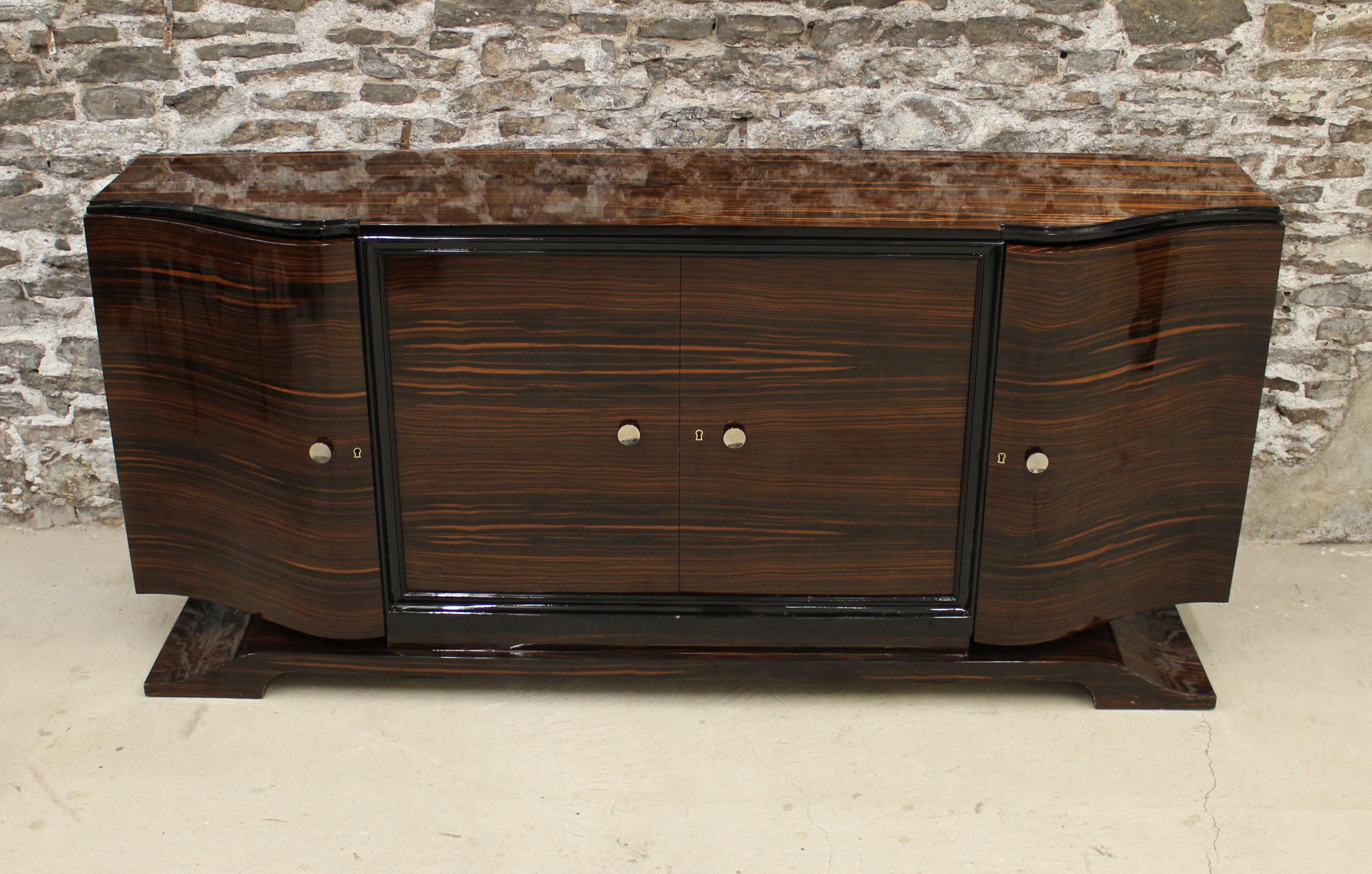 Art Deco Macassar ebony sideboard in the manner of Émile-Jacques Ruhlmann. This four-door credenza is elegantly bowed with stepped ebonized trim and chrome hardware.