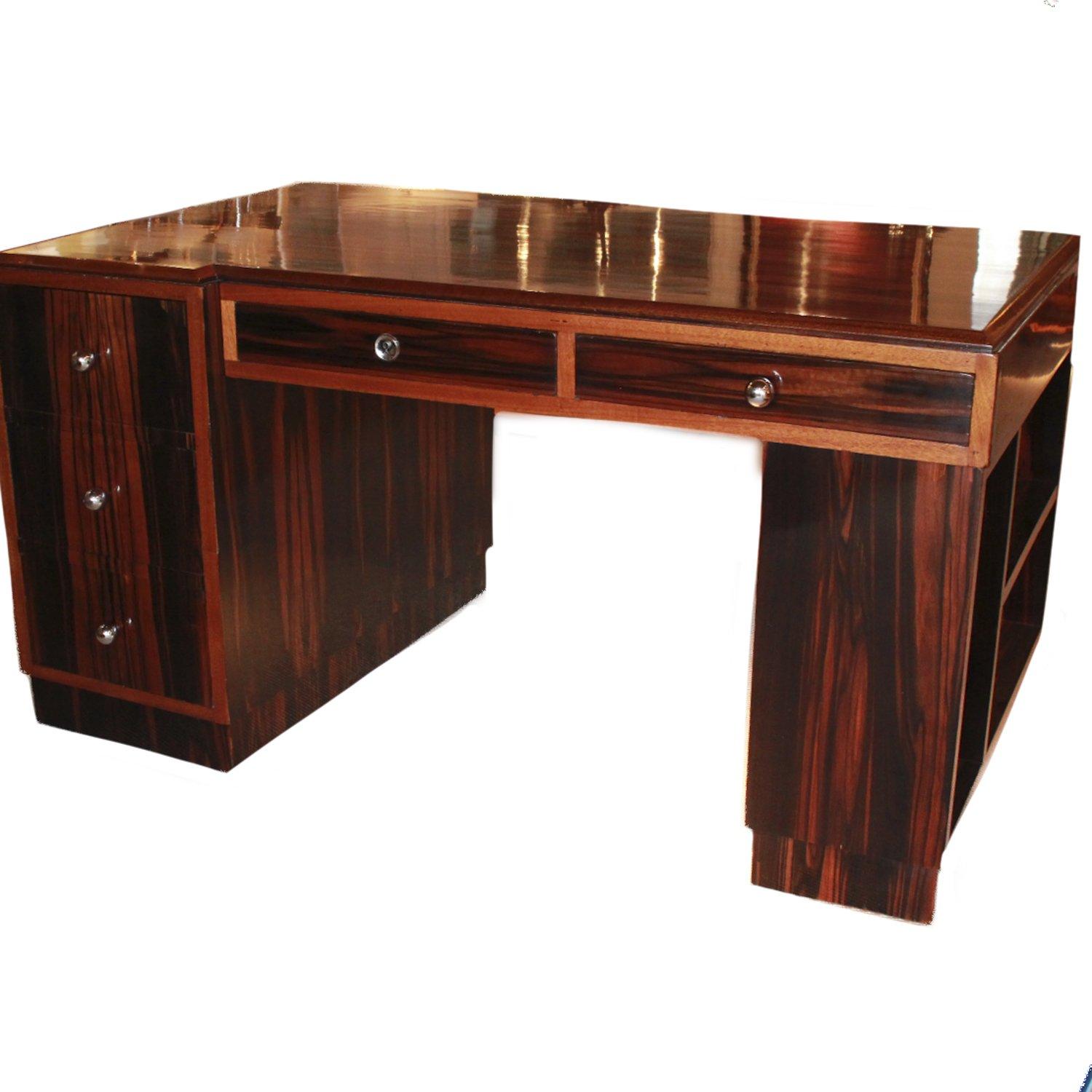 An Art Deco Macassar ebony desk with original chromed, brass handles. Three short drawers to left side pedestal with two drawers to top and library book shelves to outside pedestal. Veneered in Macassar throughout.

Dimensions: H 75cm, W 140cm, D