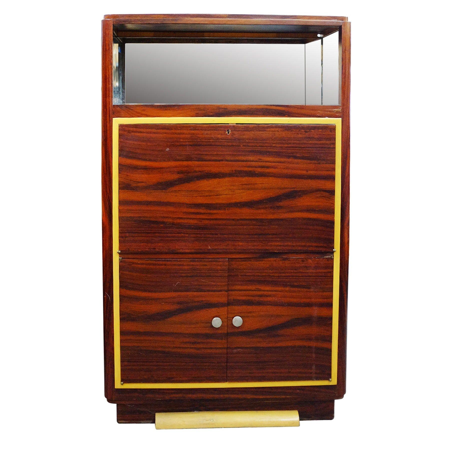 Rare late Art Deco vitrine cabinet with a medium stained Macassar veneer and mirror backed bar on top. Underneath is a fold out secretary desk with two large doors which open up to adjustable shelving for storage.

The exterior has great tall skinny