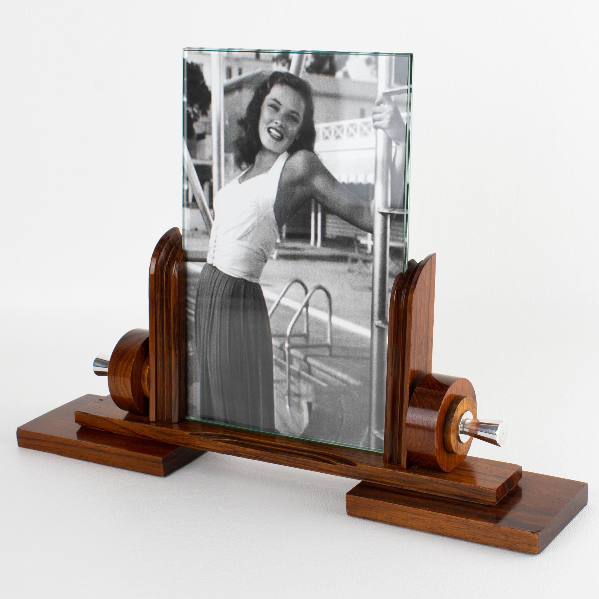 This stunning Art Deco modernist picture frame features a thick, hand-rubbed Macassar wood plinth complemented by carved Macassar wood holders and ornaments, all set off with ornate chrome accents. The photo frame is complete with two glass sheets