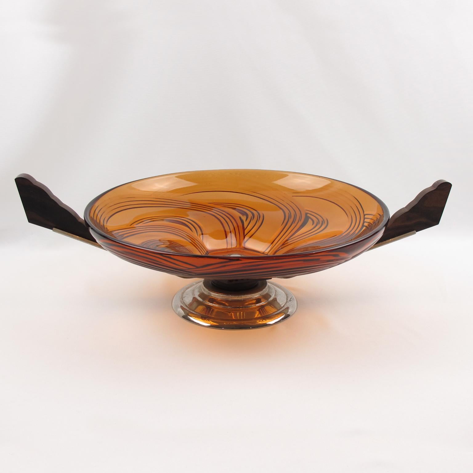 This stylish French Art Deco modernist centerpiece or bowl features a large round molded glass bowl with a swirled pattern in a lovely transparent burnt orange tone. The pedestal base is in chromed brass metal and Macassar wood. The centerpiece is