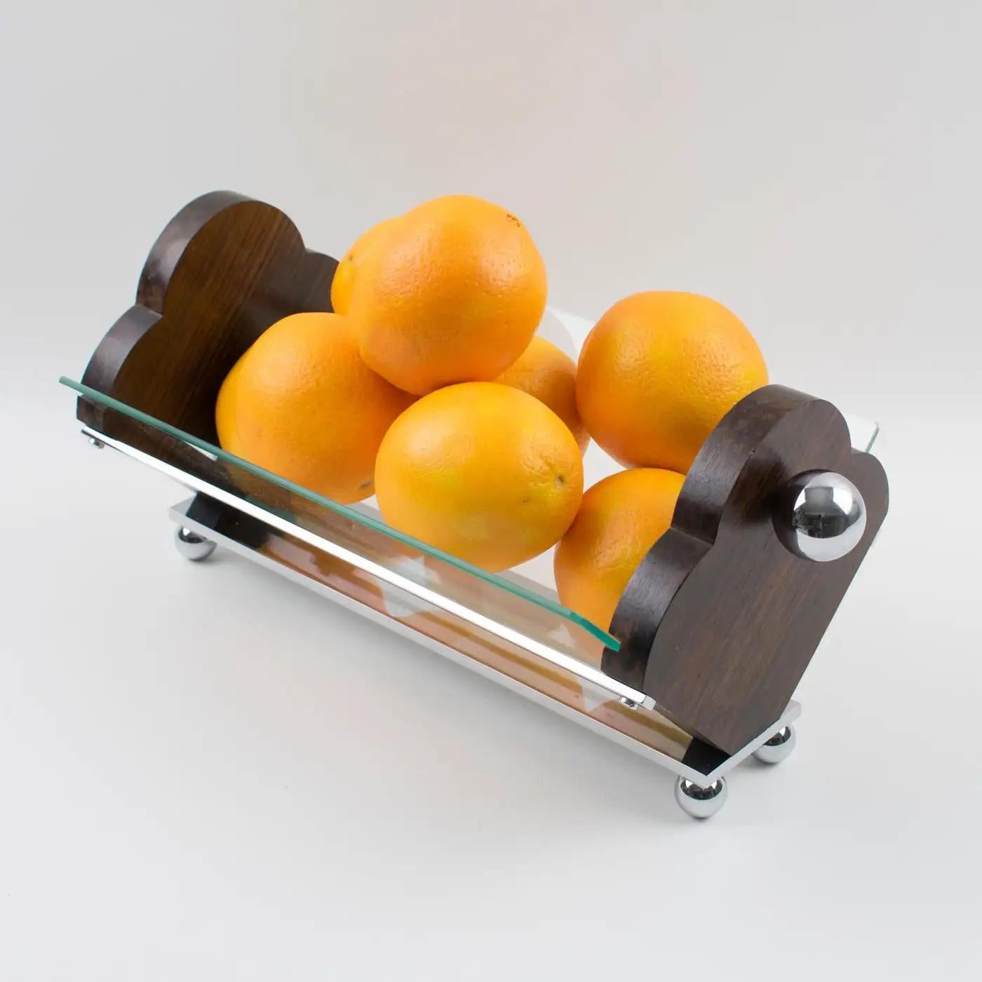 This sophisticated Art Deco centerpiece, serving bowl, or decorative fruit or bread basket was manufactured in France in the 1930s. The Macassar wood sides have two large chromed metal ball handles. A chromed metal structure holds a shaped glass
