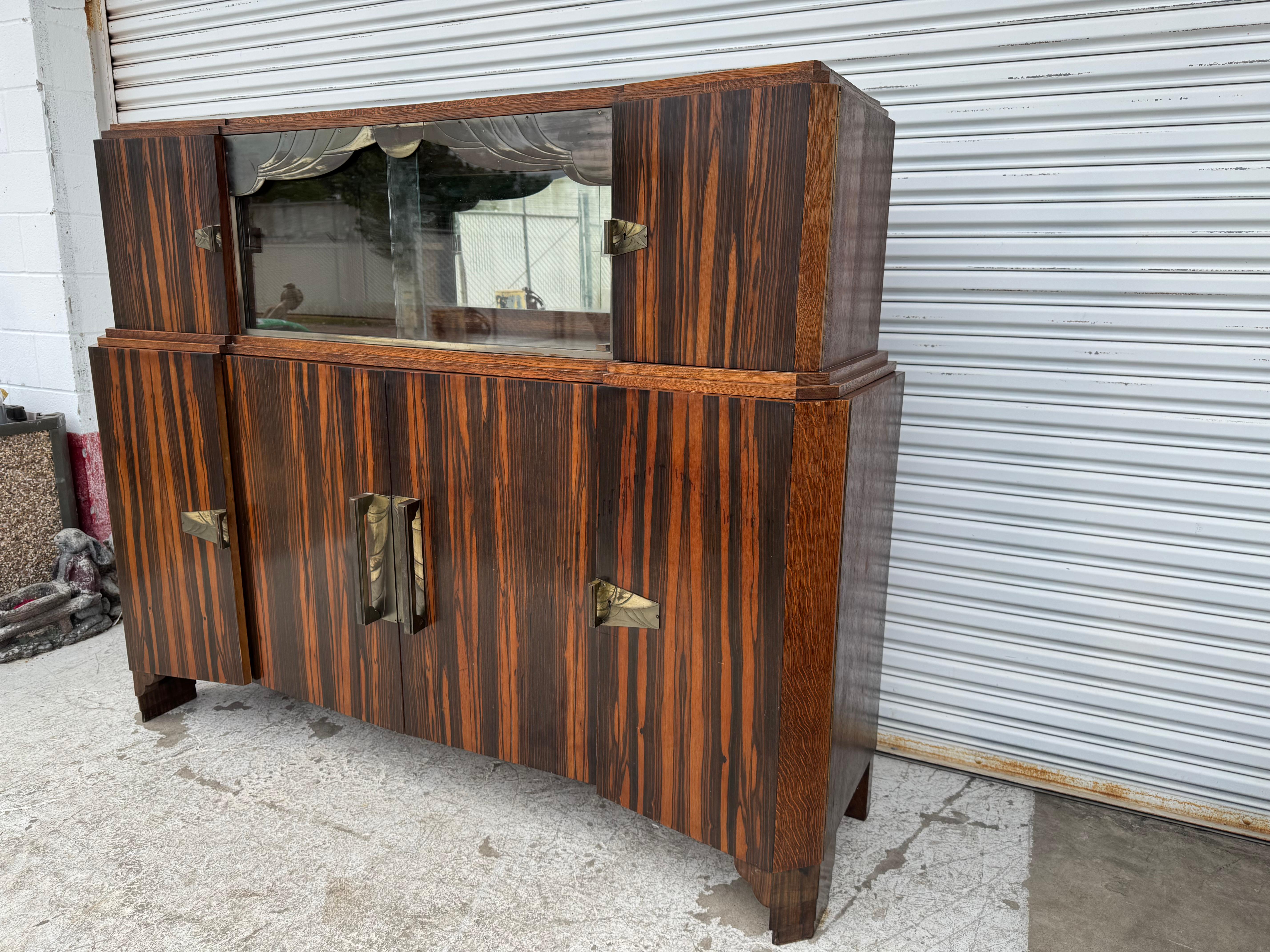 Dies ist ein schönes Art Deco Sideboard mit einer trockenen Bar. Er ist aus Makassarholz gefertigt und hat geätzte Metallbeschläge mit Messingakzenten. Die Ecken sind treppenförmig angeordnet und es gibt viel Stauraum in den unteren und oberen