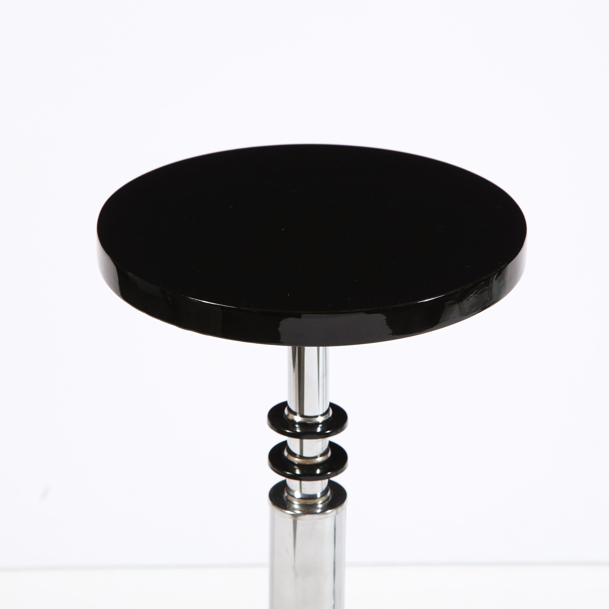 This stunning Art Deco Machine Age drinks table was realized in the United States, circa 1935. It features a circular black lacquer top, chrome body and skyscraper style black lacquer and chrome base. Additionally, circular banding detailing in