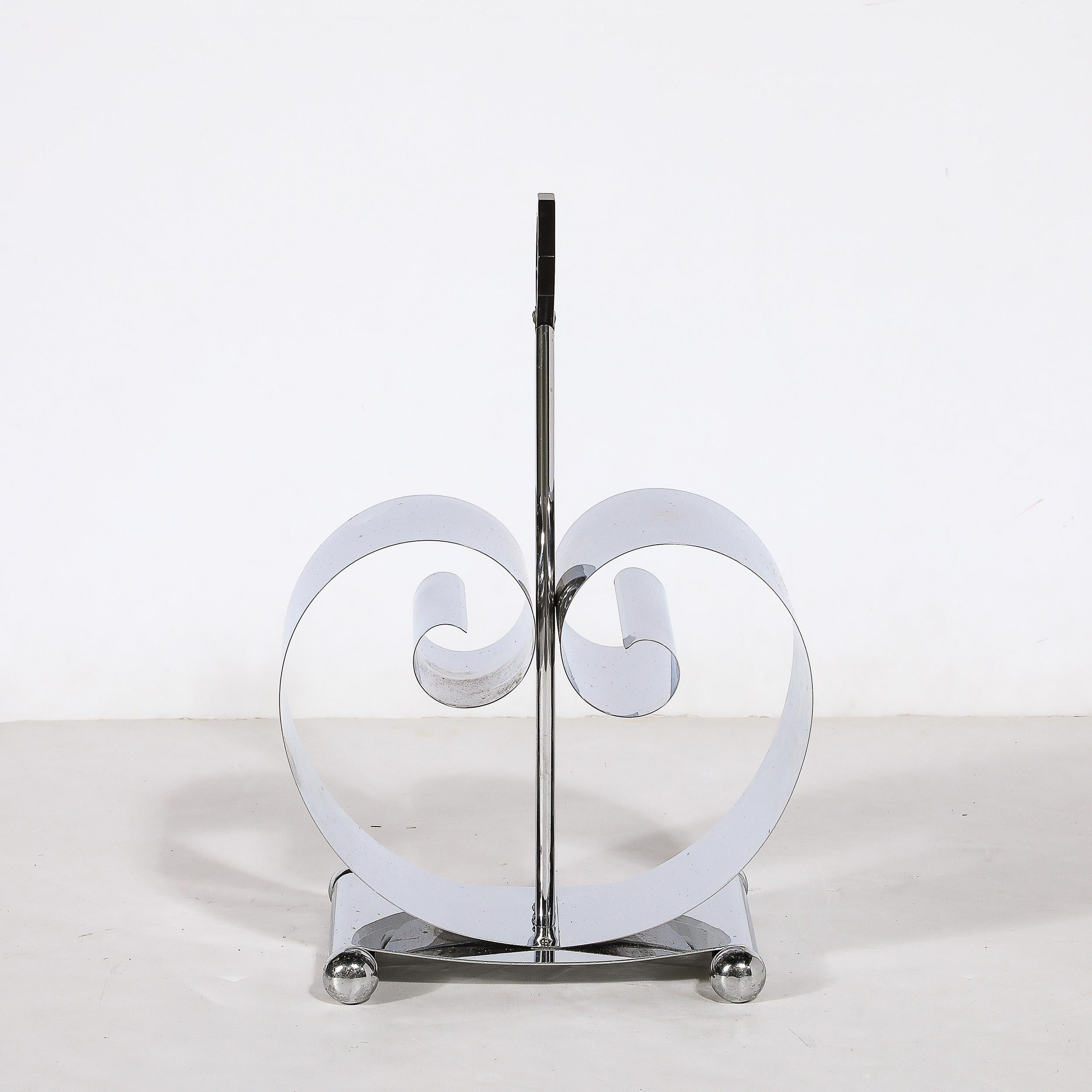This elegant magazine stand was realized in the United States by Fred Farr for Revere in America, circa 1935. Handcrafted in Rome, New York, this piece offers a banded and streamlined black enamel base from which two curling chrome scroll forms